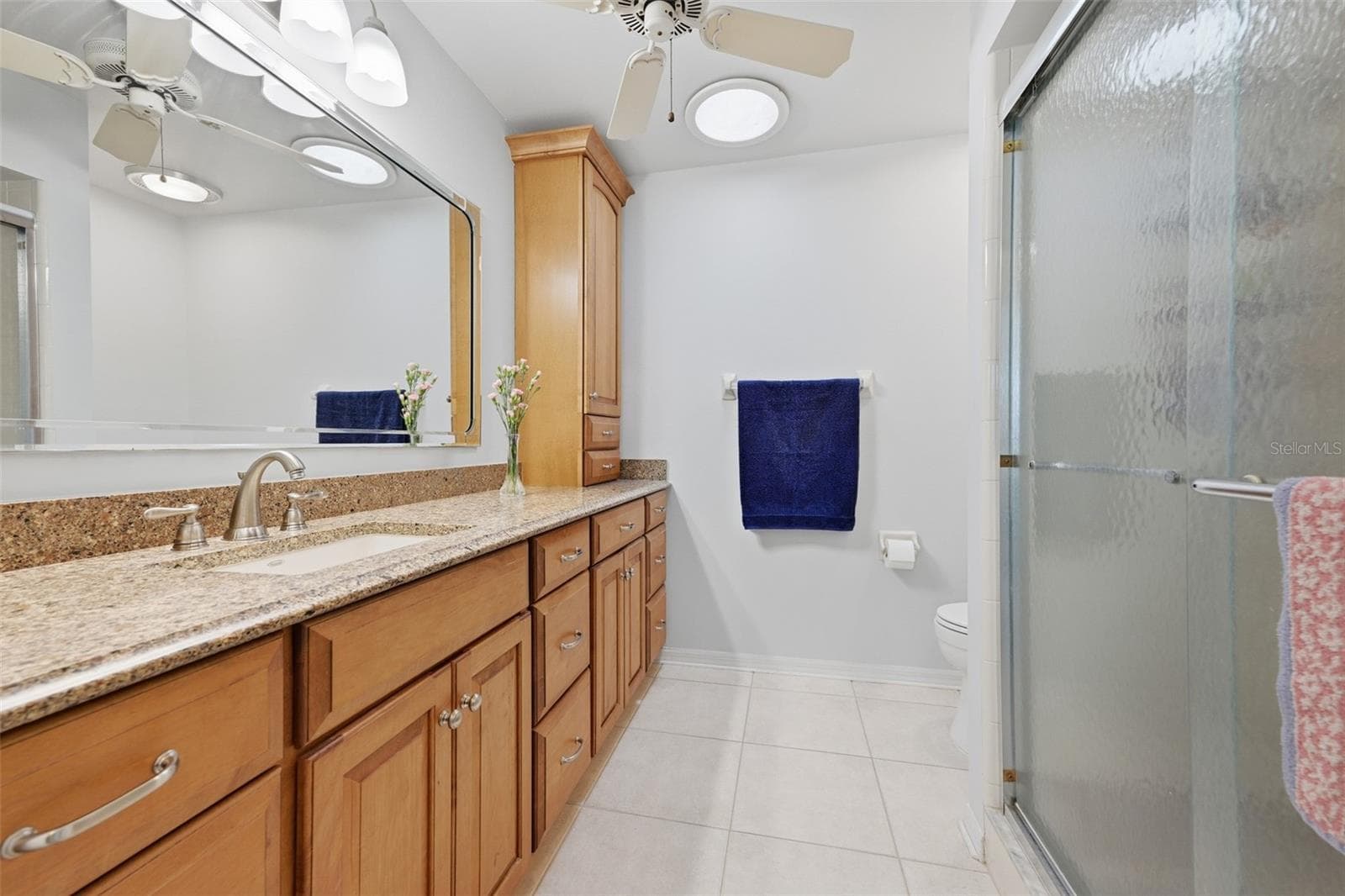 UPDATED GUEST BATHROOM WITH RAISED VANITY, LOADS OF STORAGE, GLASS ENCLOSED SHOWER, SOLAR TUBE AND COMFORT HEIGHT TOILET. - 1803 NEW BEDFORD DR, SUN CITY CENTER