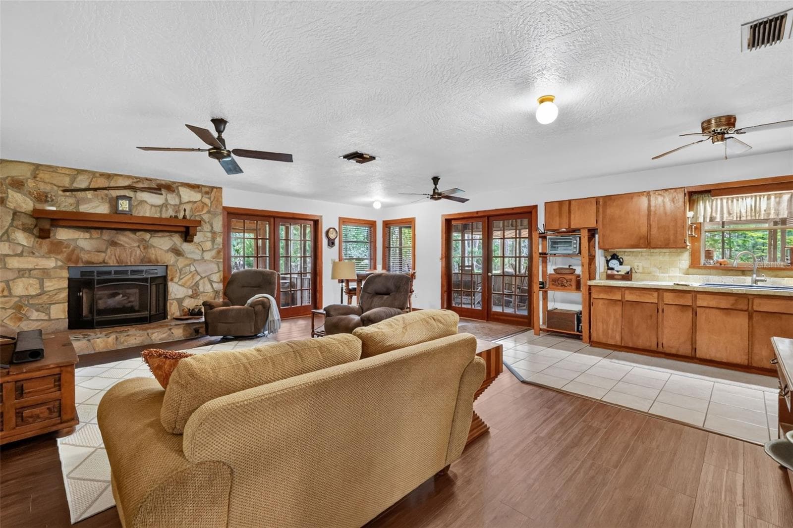 View into great room from side porch featuring main entry French doors as well as French doors to another side porch, gas fireplace, dinette and kitchen - 24939 OLD DEER RD, PAISLEY