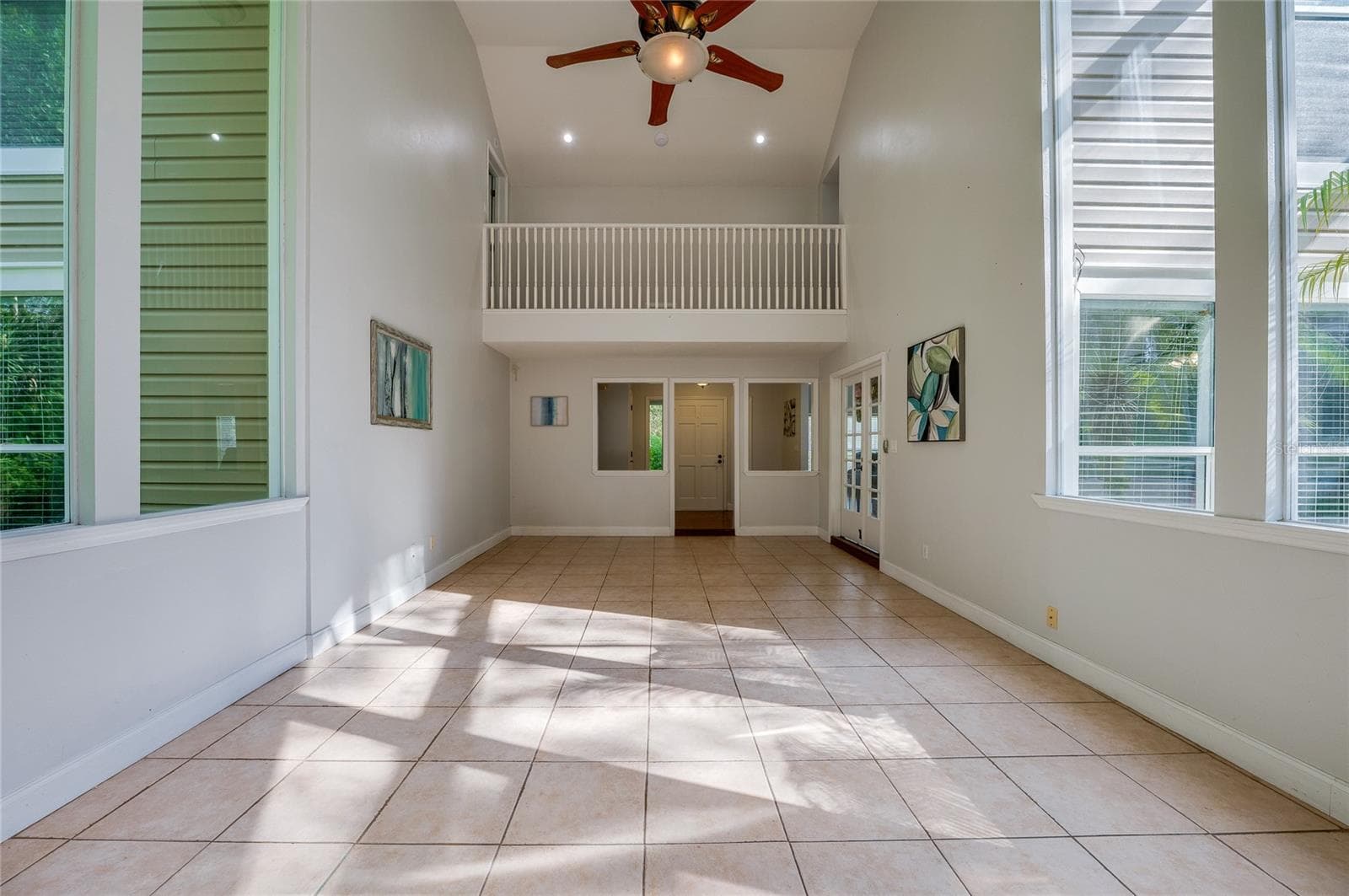 Expansive two-story living area with high ceilings, large windows, tiled flooring, and a overlook balcony on the upper level. - 2081 PENNSYLVANIA DR, DELAND