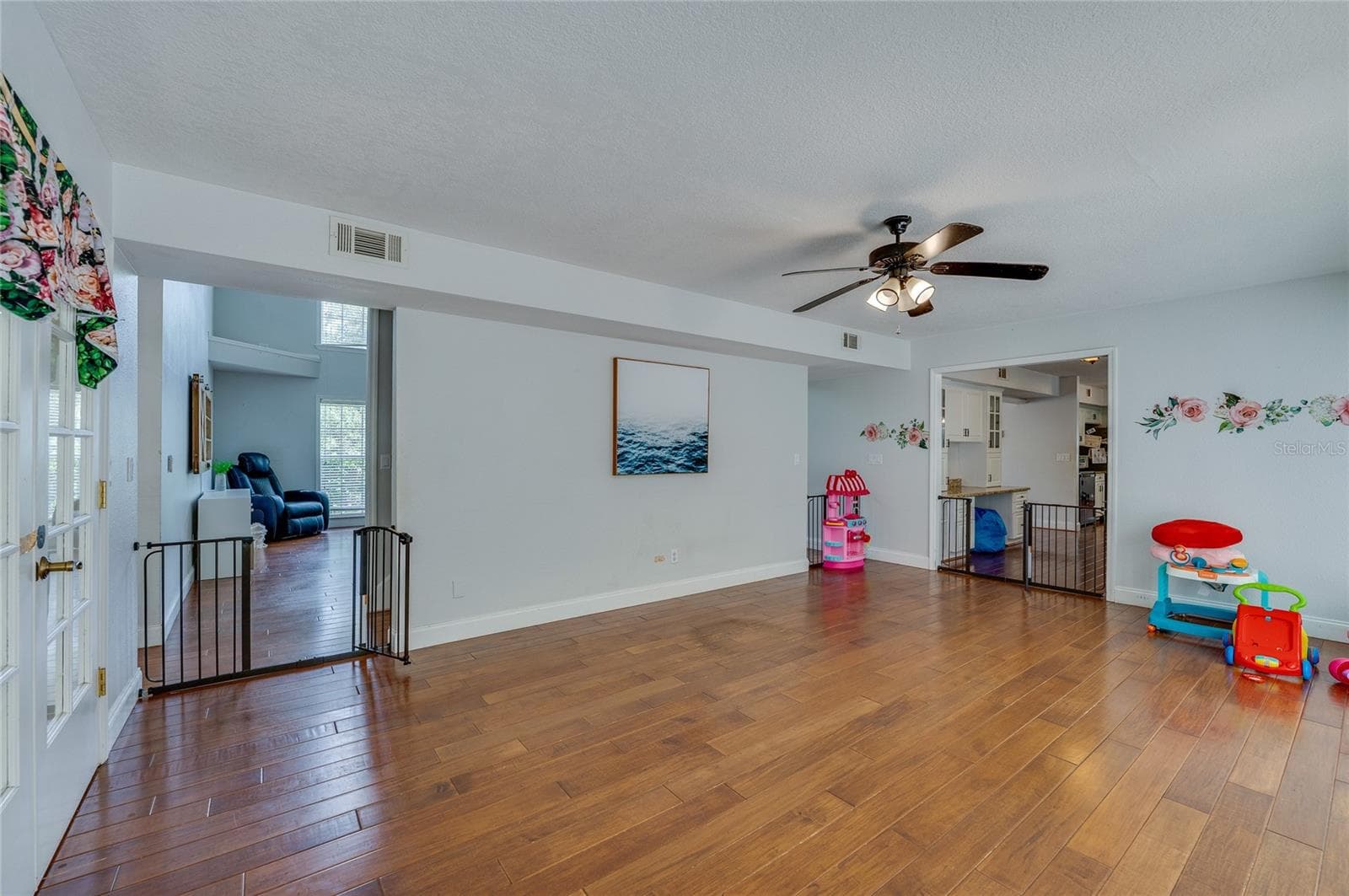 Versatile open room with rich laminate floors, a ceiling fan, and wide archway entrances connecting to surrounding living spaces. - 2081 PENNSYLVANIA DR, DELAND