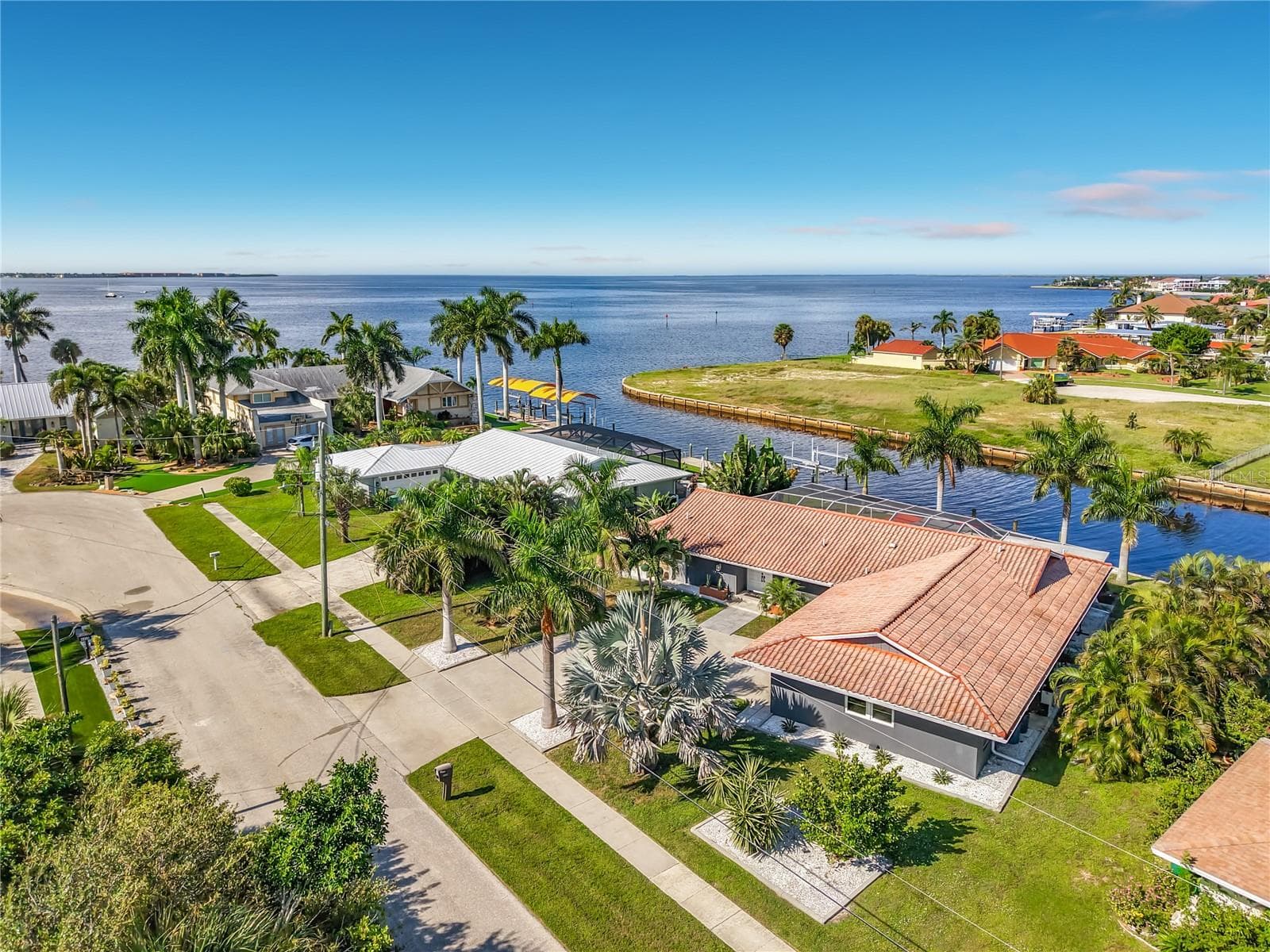 Aerial View – Aerial view showcasing the waterfront property, surrounding neighborhood, canal, and expansive water beyond. - 4449 CREWS CT, PORT CHARLOTTE