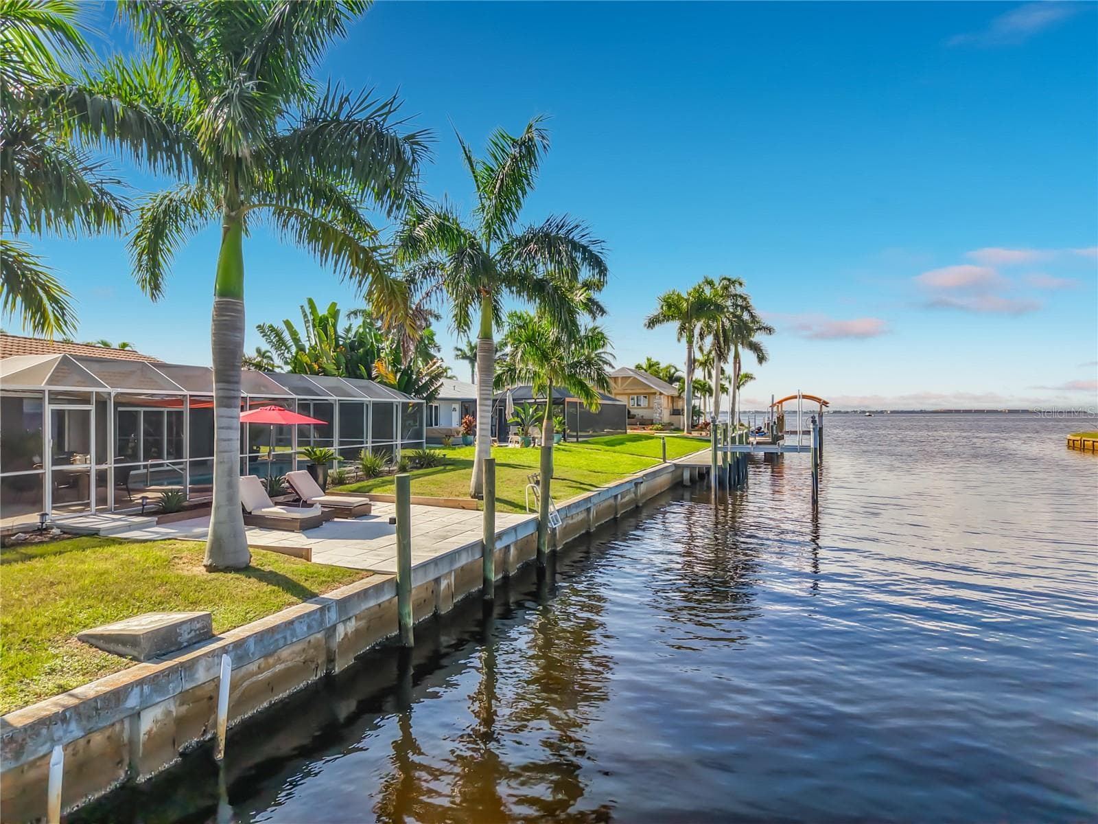 Waterfront & Seawall – Waterfront view from the property showcasing the canal, seawall, tropical landscaping, and open-water setting. - 4449 CREWS CT, PORT CHARLOTTE