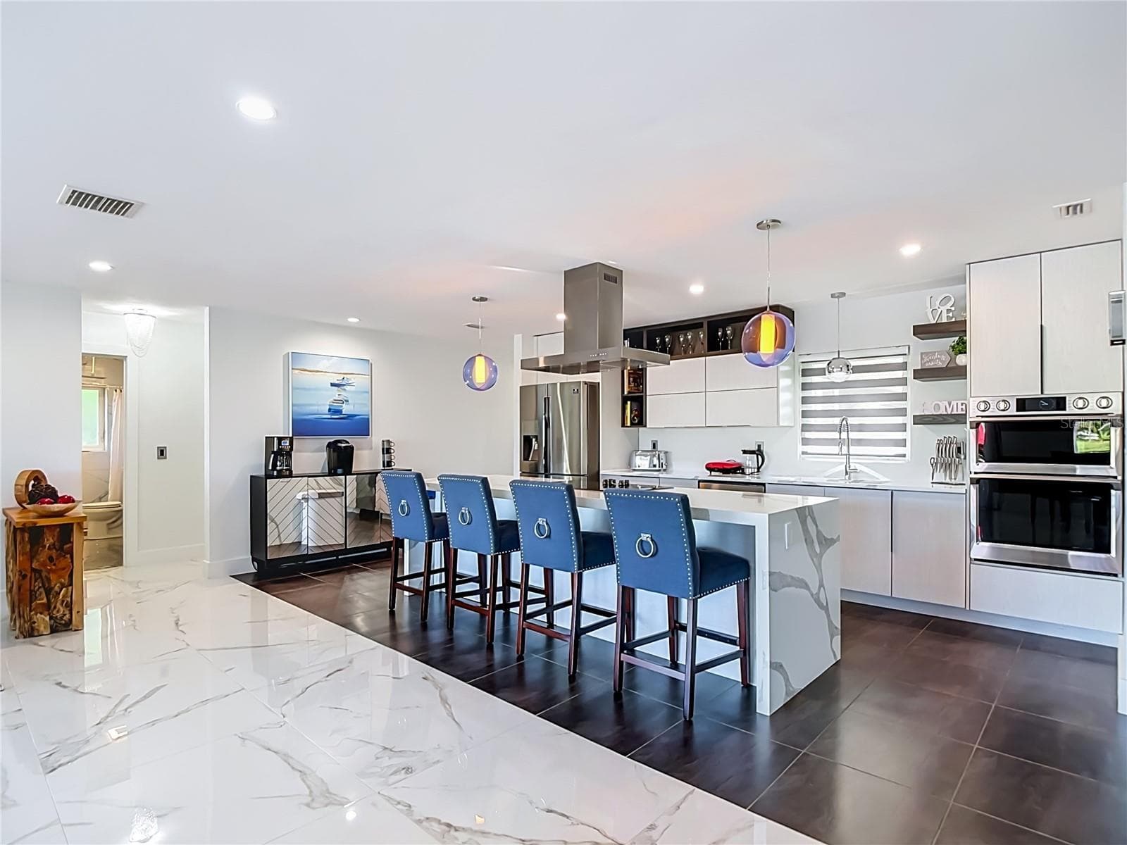 itchen & Island – Bright contemporary kitchen featuring a large center island with seating, modern cabinetry, and an open layout. - 4449 CREWS CT, PORT CHARLOTTE
