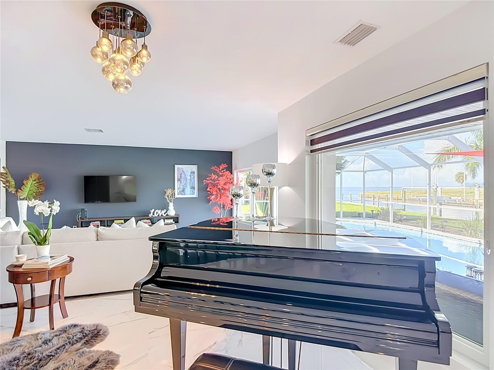 iving Area – Bright living and entertainment area featuring large windows overlooking the screened outdoor living space and pool. - 4449 CREWS CT, PORT CHARLOTTE