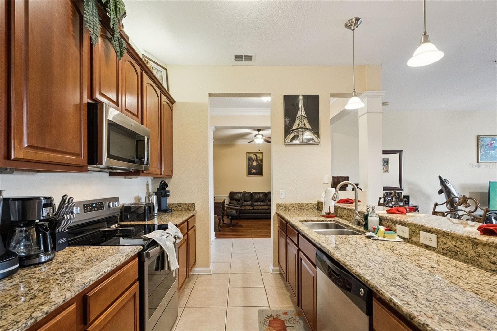 Kitchen Appliances & Cabinetry:Well-equipped kitchen featuring warm wood cabinetry, granite countertops, built-in microwave, glass-top range, and tiled flooring. - 4840 CAYVIEW AVE #405, ORLANDO