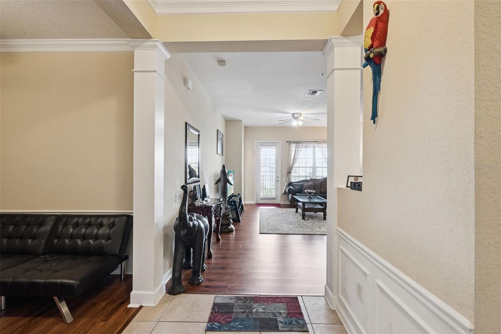 Main Hallway Transition:Gallery-style hallway featuring rich wood-look flooring, architectural columns, and direct sightlines through to the main living area. - 4840 CAYVIEW AVE #405, ORLANDO