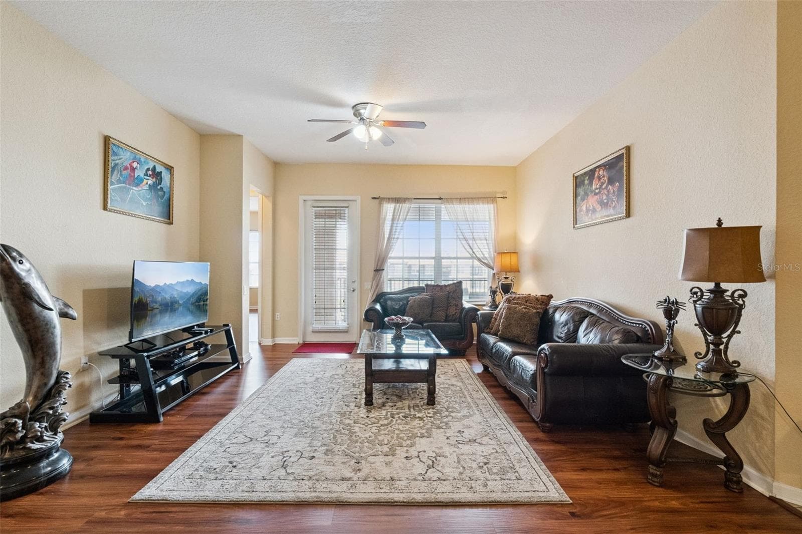 Living Room View:Light-filled living room featuring wood-look plank flooring, smooth ceilings, ceiling fan, and open views toward the balcony. - 4840 CAYVIEW AVE #405, ORLANDO
