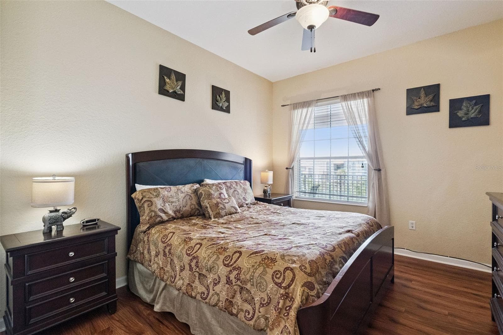 Bedroom Suite Layout:Inviting bedroom with a dark wood bed frame, matching nightstands with decorative lamps, ceiling fan, and warm wood-look plank flooring. - 4840 CAYVIEW AVE #405, ORLANDO