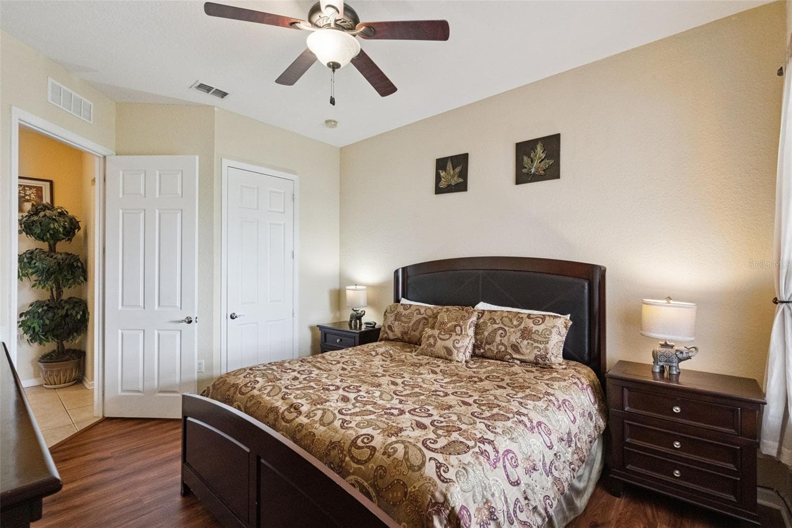 Bedroom Closet & Hallway Access:Bedroom view displaying dark wood furnishings, ceiling fan, neutral wall tones, wood-look floors, and convenient access to closet and entryway doors. - 4840 CAYVIEW AVE #405, ORLANDO