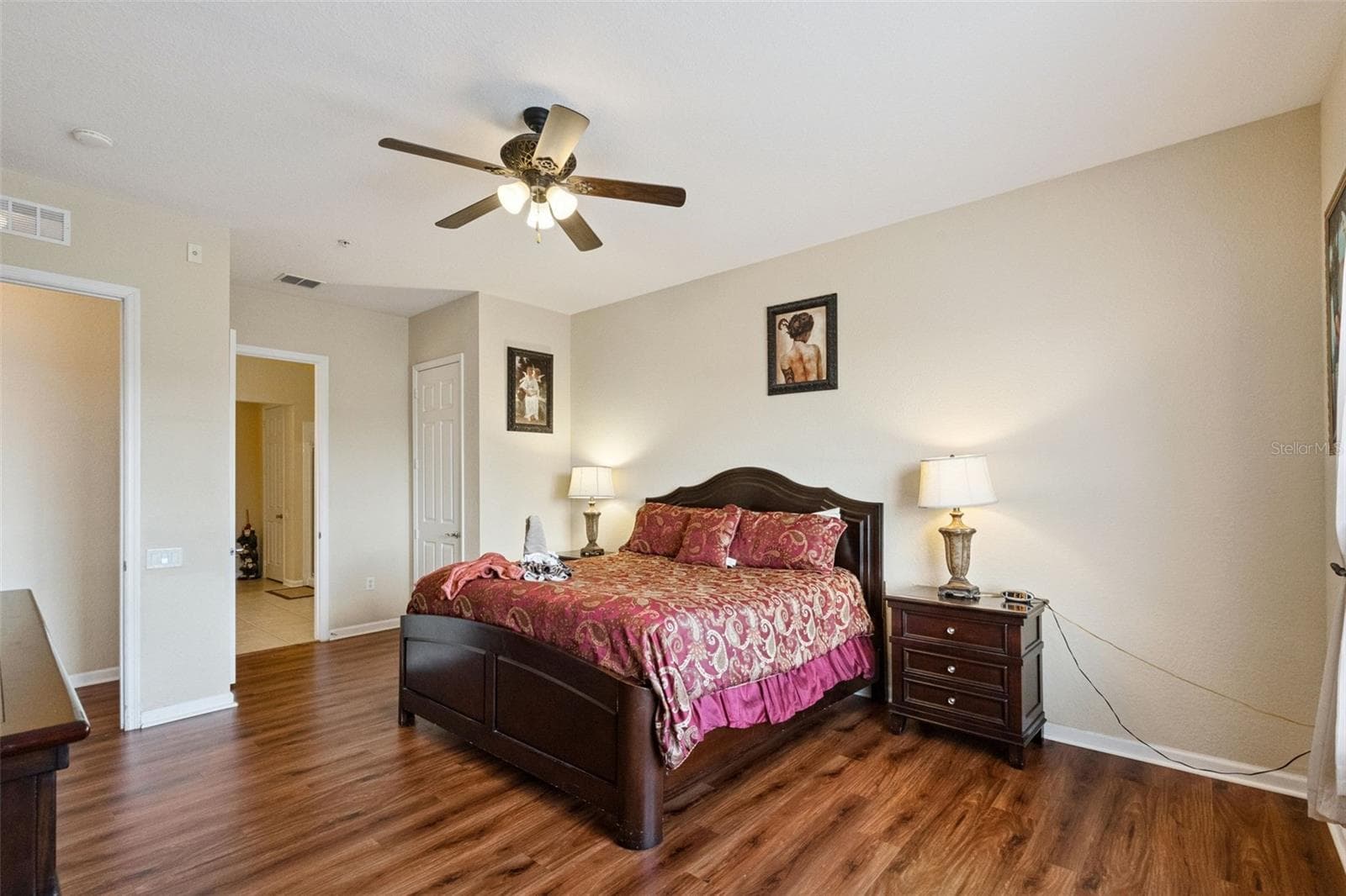 Primary Suite Perspective:Generously sized primary bedroom highlighting seamless access to the en-suite bathroom, closet storage, ceiling fan, and low-maintenance wood-look flooring. - 4840 CAYVIEW AVE #405, ORLANDO