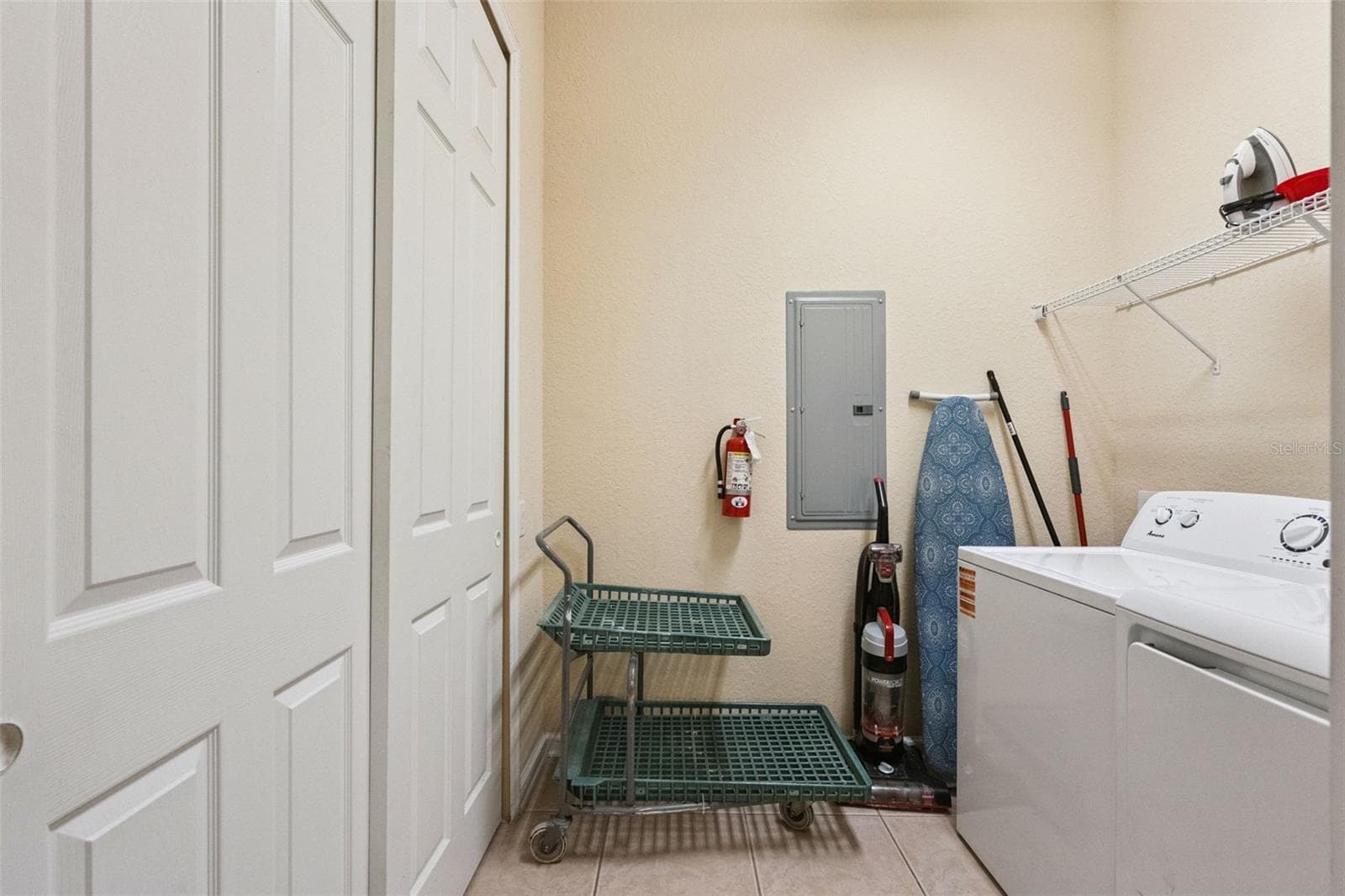 Laundry Room & Storage:Dedicated laundry room equipped with a full-size washer and dryer, double storage closet, upper wire shelf, and low-maintenance tiled flooring. - 4840 CAYVIEW AVE #405, ORLANDO