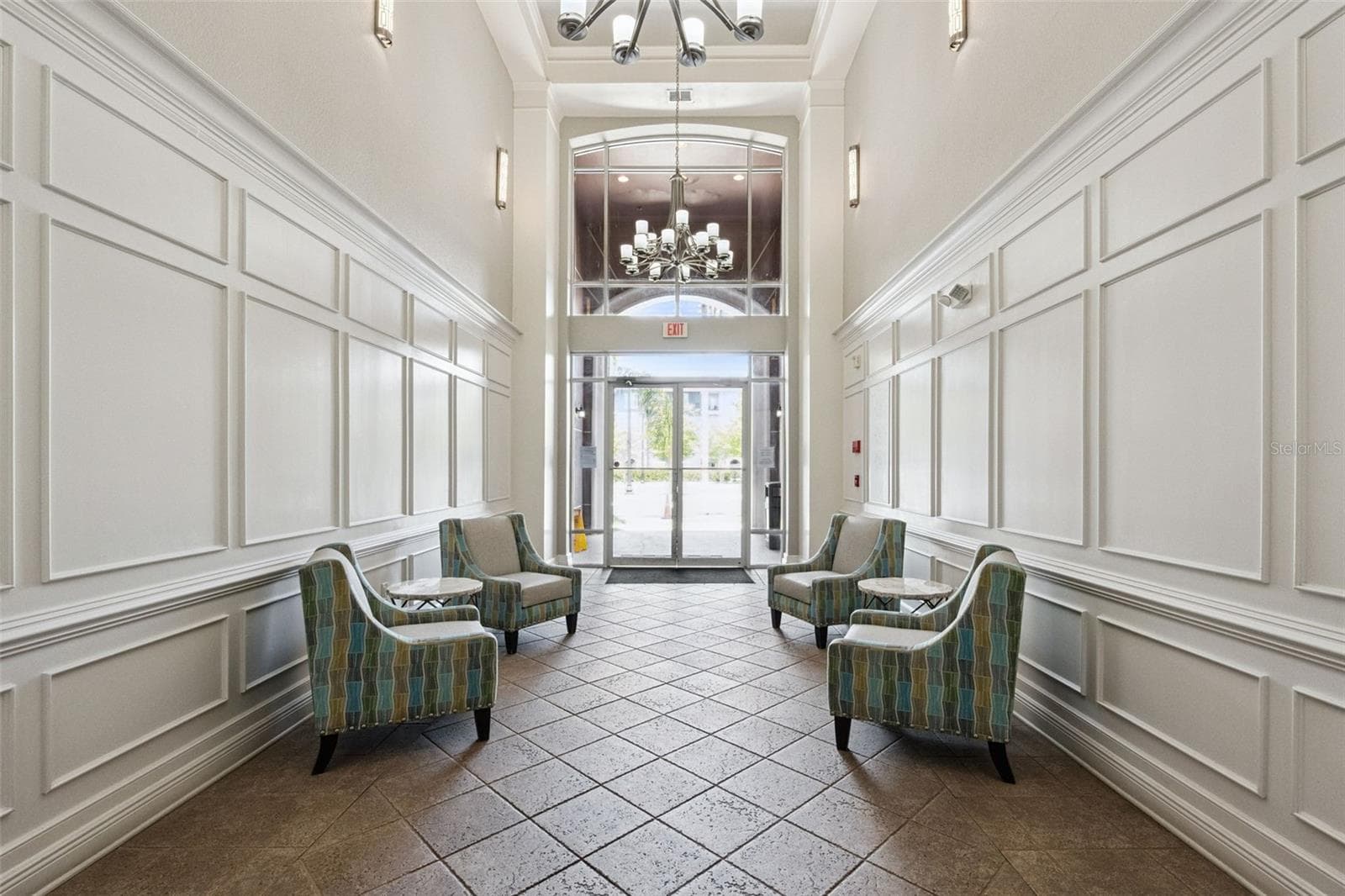 Building Lobby:Elegant main lobby showcasing classic wall trim and paneling, high ceilings, chandelier lighting, tiled floors, and comfortable sitting areas. - 4840 CAYVIEW AVE #405, ORLANDO