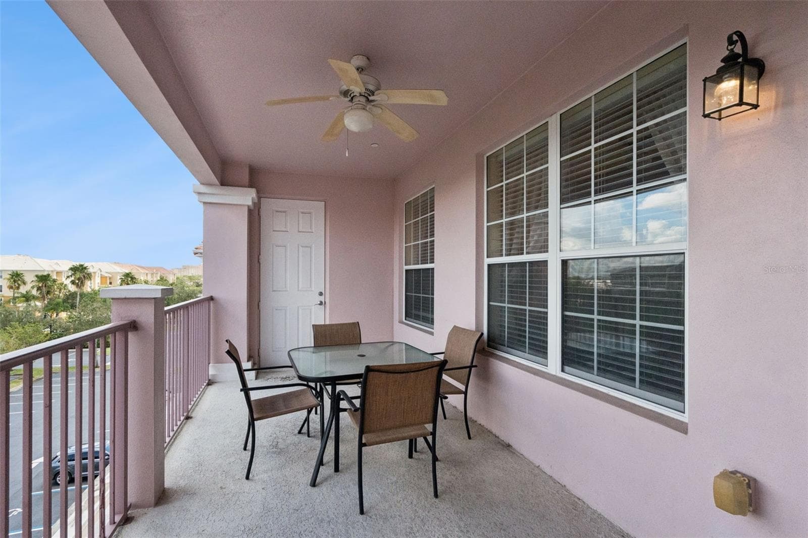 Balcony Wall & Windows:Private covered balcony highlighting large multi-pane windows, exterior wall lighting, ceiling fan, and patio seating. - 4840 CAYVIEW AVE #405, ORLANDO