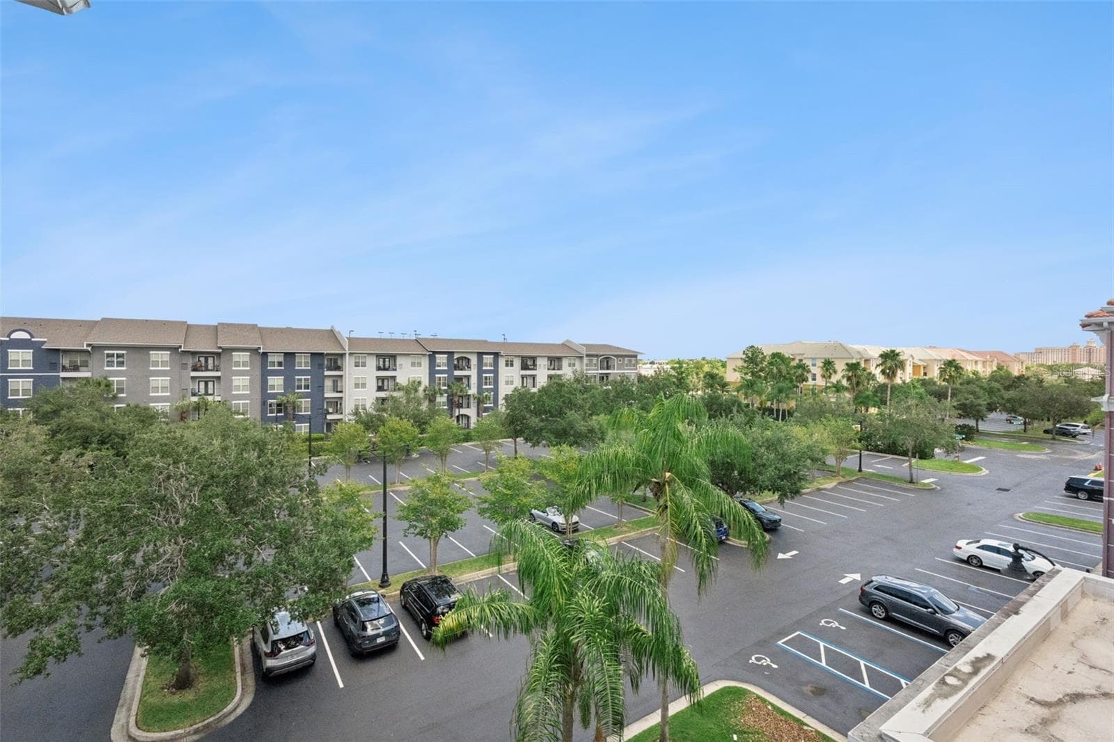 Front Aerial View:Elevated balcony perspective overlooking landscaped community grounds, mature shade trees, and parking facilities under open skies. - 4840 CAYVIEW AVE #405, ORLANDO