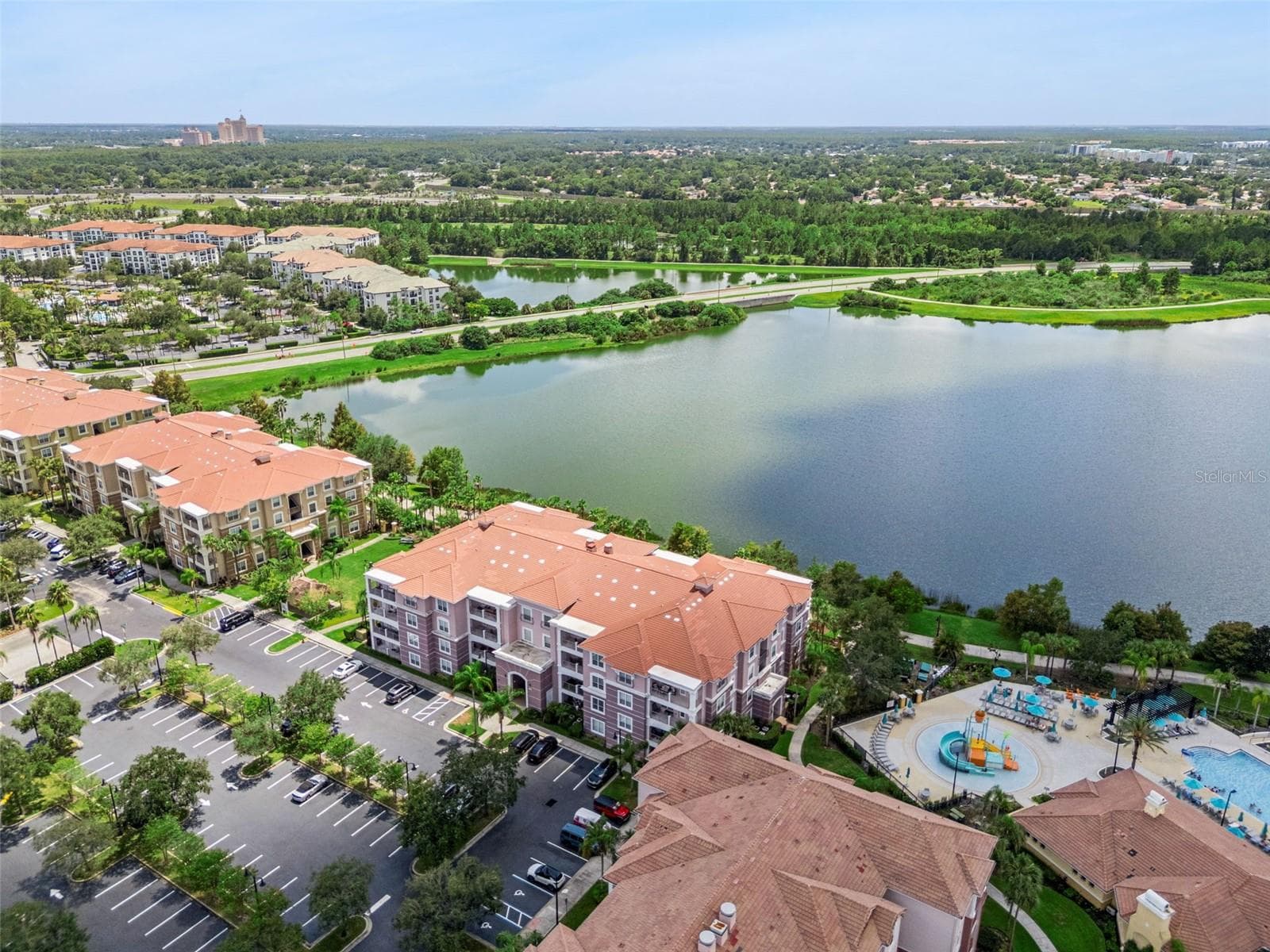 Resort & Waterfront Aerial:High aerial view capturing the building, splash pad, main resort pool, parking layout, and sweeping lake views. - 4840 CAYVIEW AVE #405, ORLANDO
