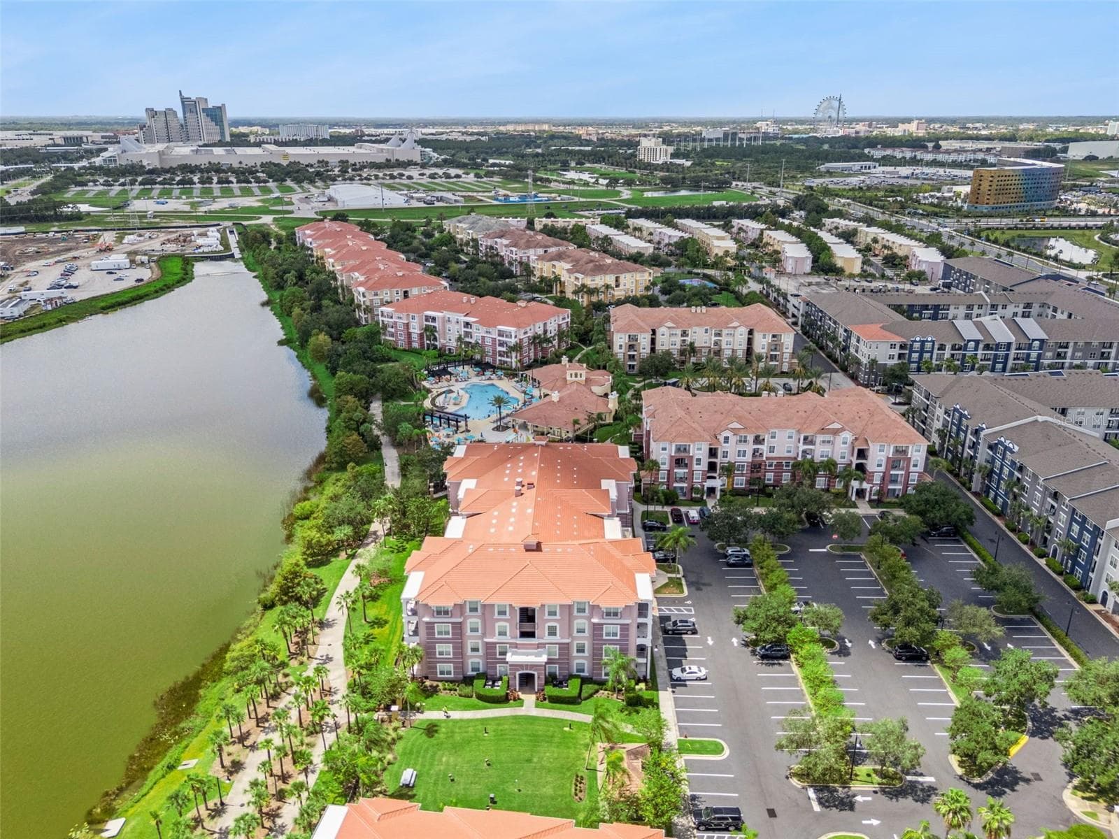 Skyline & Lakefront Aerial:Wide aerial overview featuring the lakefront walking trail, manicured grounds, parking area, and distant views of local attractions. - 4840 CAYVIEW AVE #405, ORLANDO