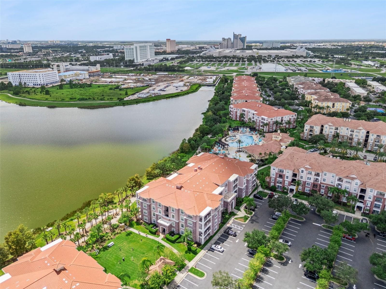 Building Grounds Aerial:Elevated aerial shot showcasing the manicured lawn, extensive parking, lake shoreline, and close proximity to key convention centers and resorts. - 4840 CAYVIEW AVE #405, ORLANDO