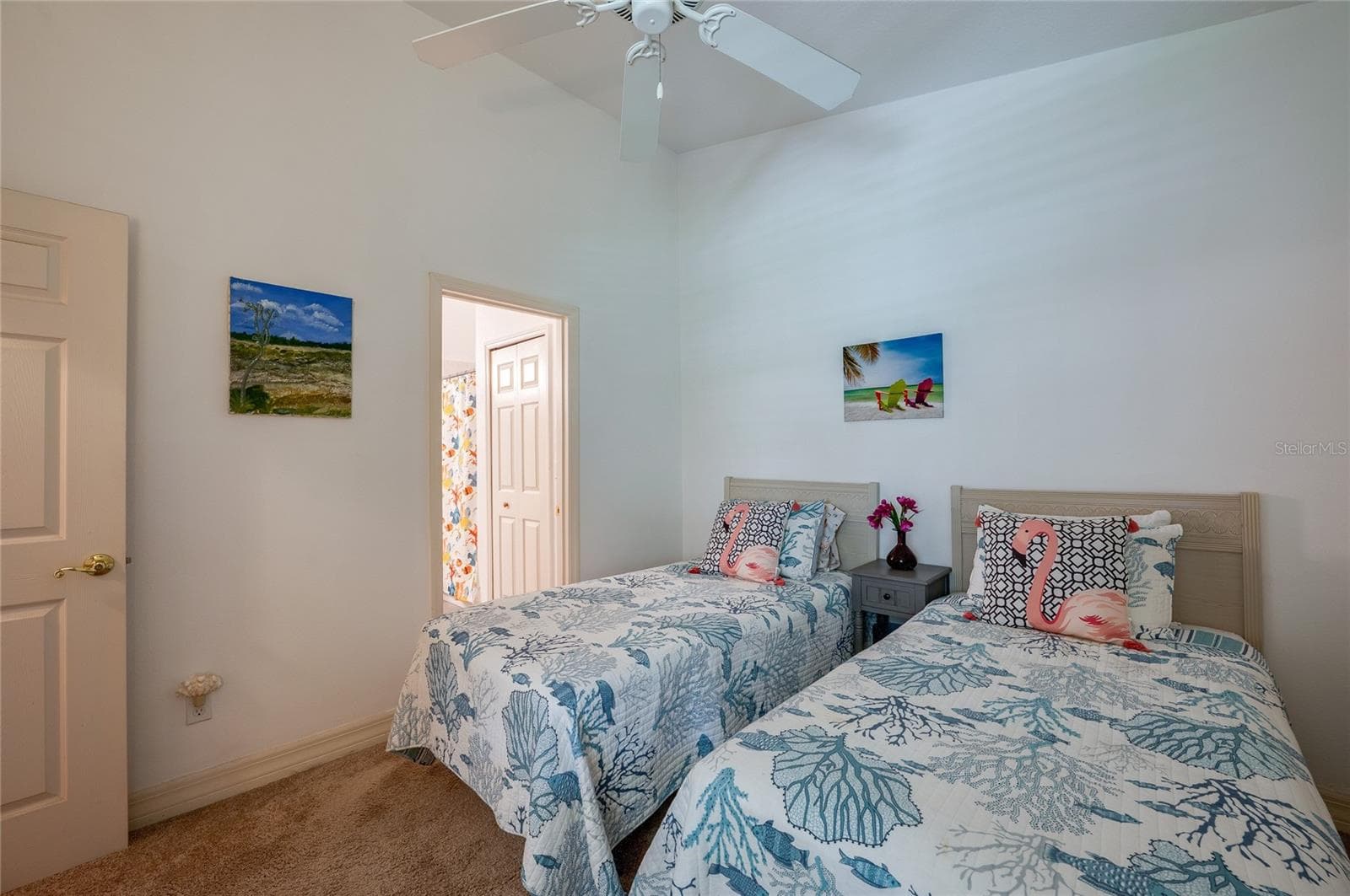 Inviting bedroom layout framed by soft neutral walls, high ceilings, and plush carpeting. An open doorway offers direct access to an adjacent full bathroom. - 1413 COCONUT PALM CIR, PORT ORANGE