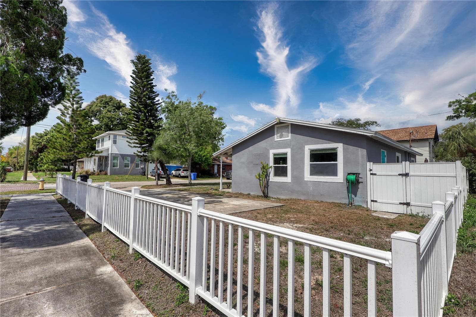 A charming white picket-style fence partially borders the front yard, while taller vinyl privacy fencing defines the main home’s private side area. - 116 44TH ST S, ST PETERSBURG