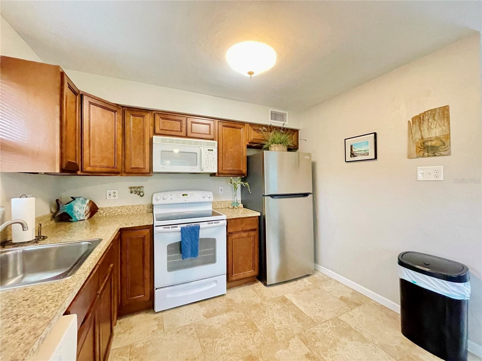 A closer view highlights the abundant cabinetry and counter space, stainless steel refrigerator, electric range, built-in microwave, and convenient workspace. - 723 STEELE AVE, SOUTH DAYTONA