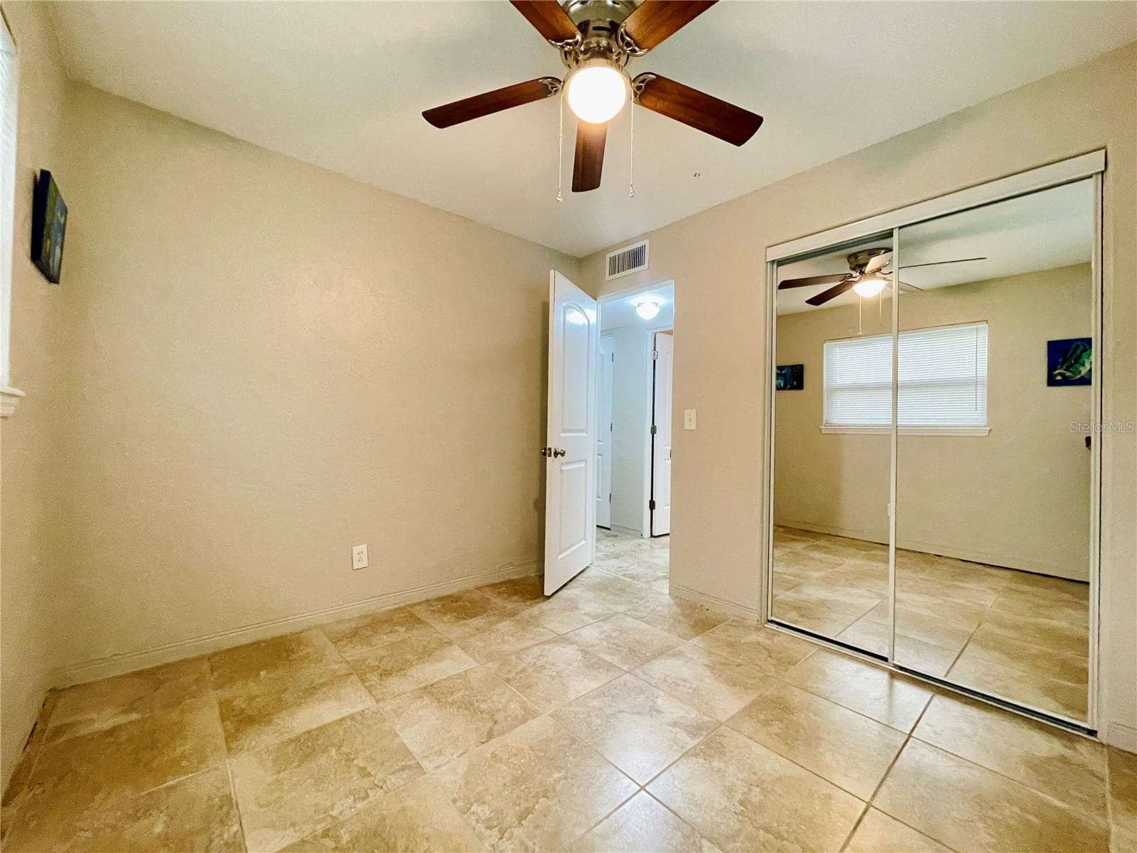 A second view of the guest bedroom highlights the mirrored closet doors, providing convenient storage while reflecting light throughout the room. - 723 STEELE AVE, SOUTH DAYTONA