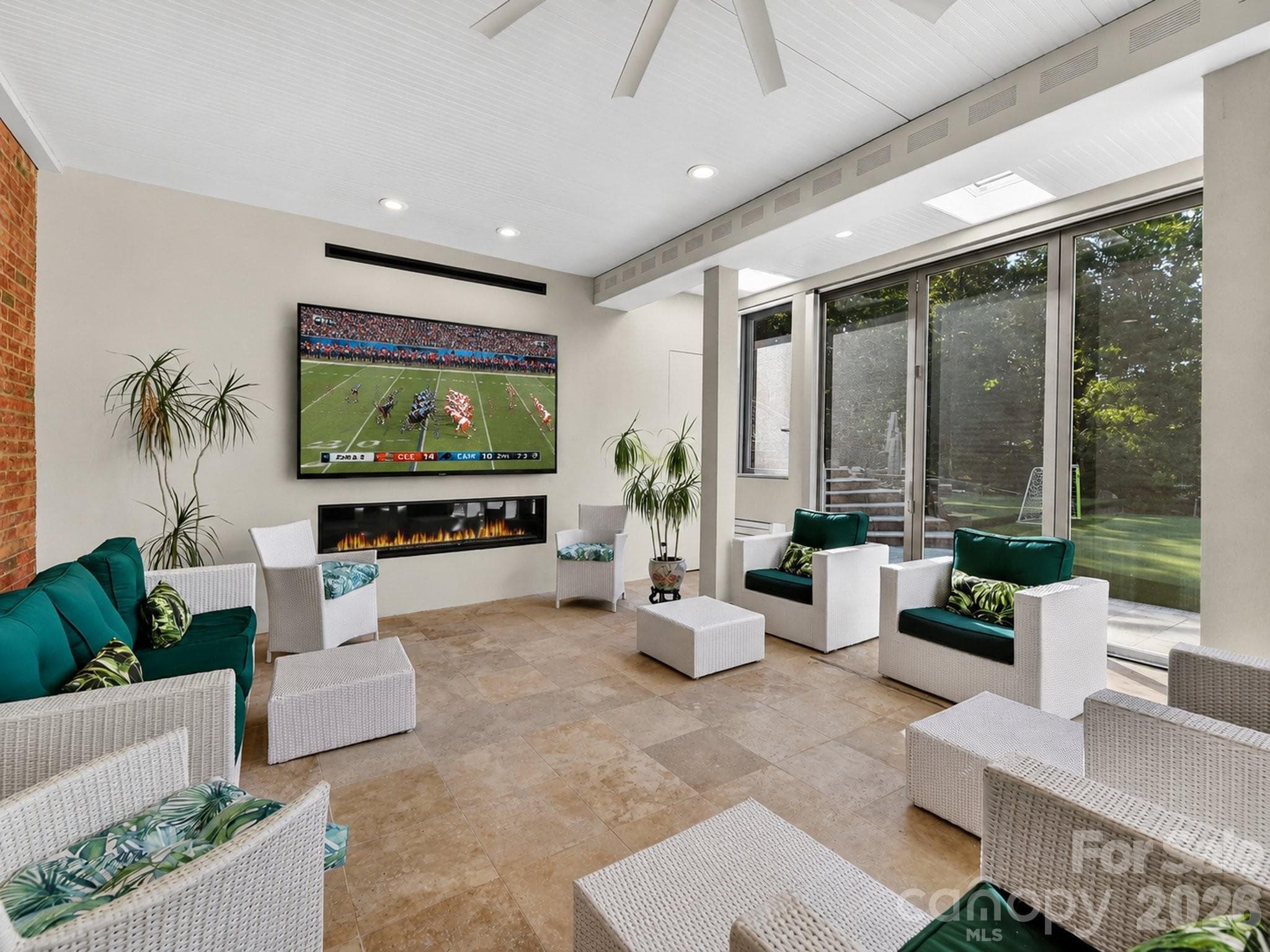 This family room is an exceptional entertaining space with heated Travertine flooring, a linear fireplace, TV and doors which can be screened or opened. - 2723 Providence Pine Lane, Charlotte