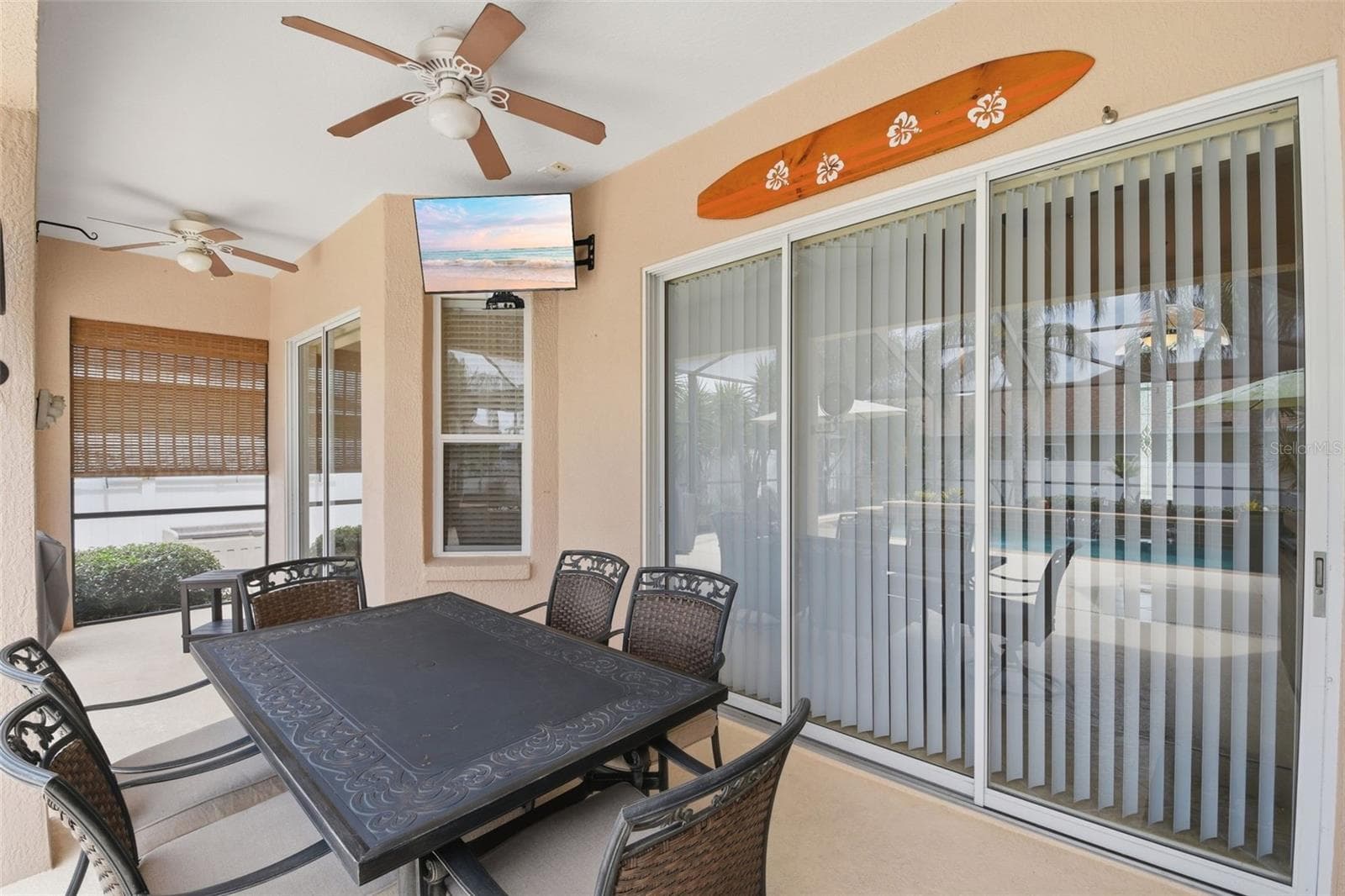 Covered Lanai – This additional lanai view highlights the shaded dining area, ceiling fans, and wide sliding glass doors connecting the outdoor space to the interior. - 114 VIOLA DR, AUBURNDALE
