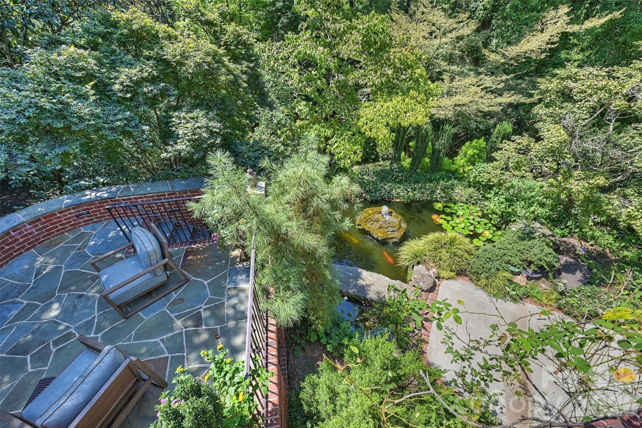 Koi pond with fountain, as seen from back porch with view of terraced patio. - 2115 Foxcroft Woods Lane, Charlotte