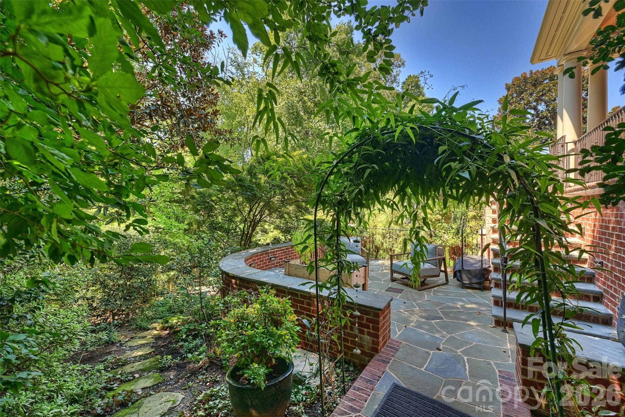 Terraced patio with view of lush backyard landscaping and winding garden trails. - 2115 Foxcroft Woods Lane, Charlotte