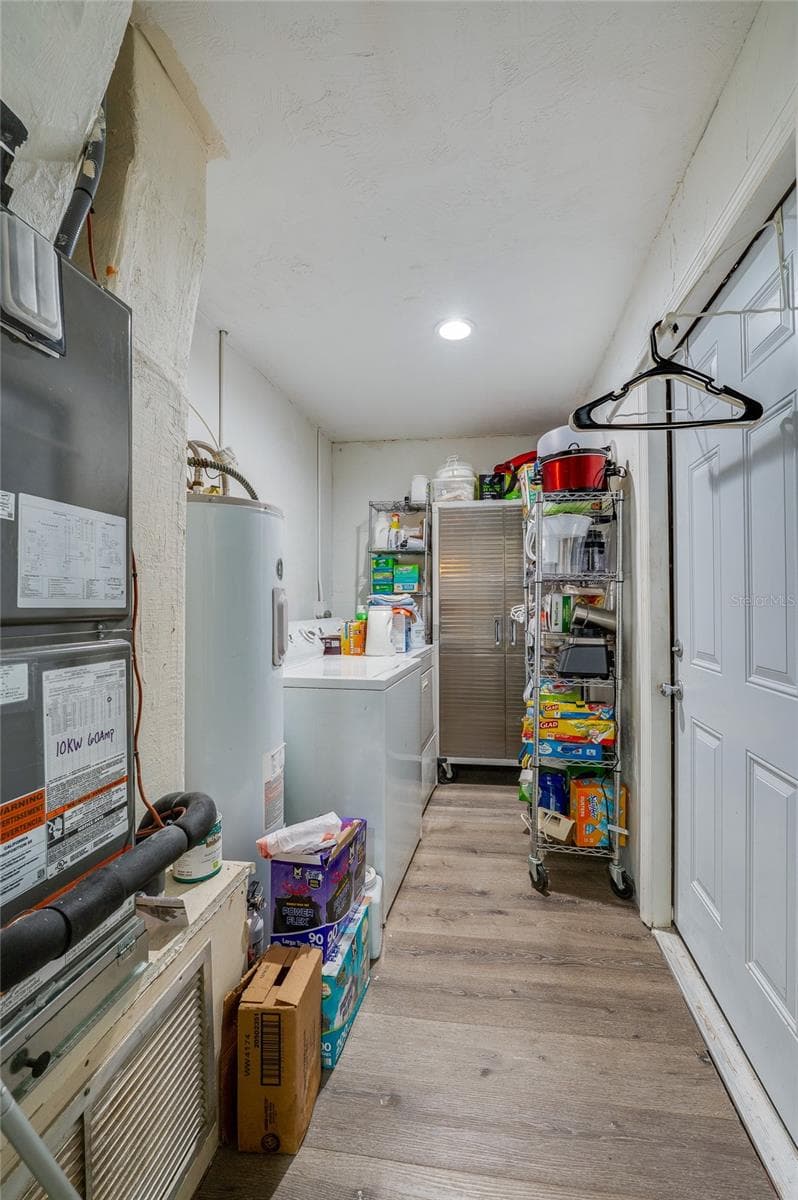Utility and laundry corridor featuring LVP flooring, white cabinetry storage, and dedicated space for a washer and dryer. - 146 WESTWOOD DR, DAYTONA BEACH