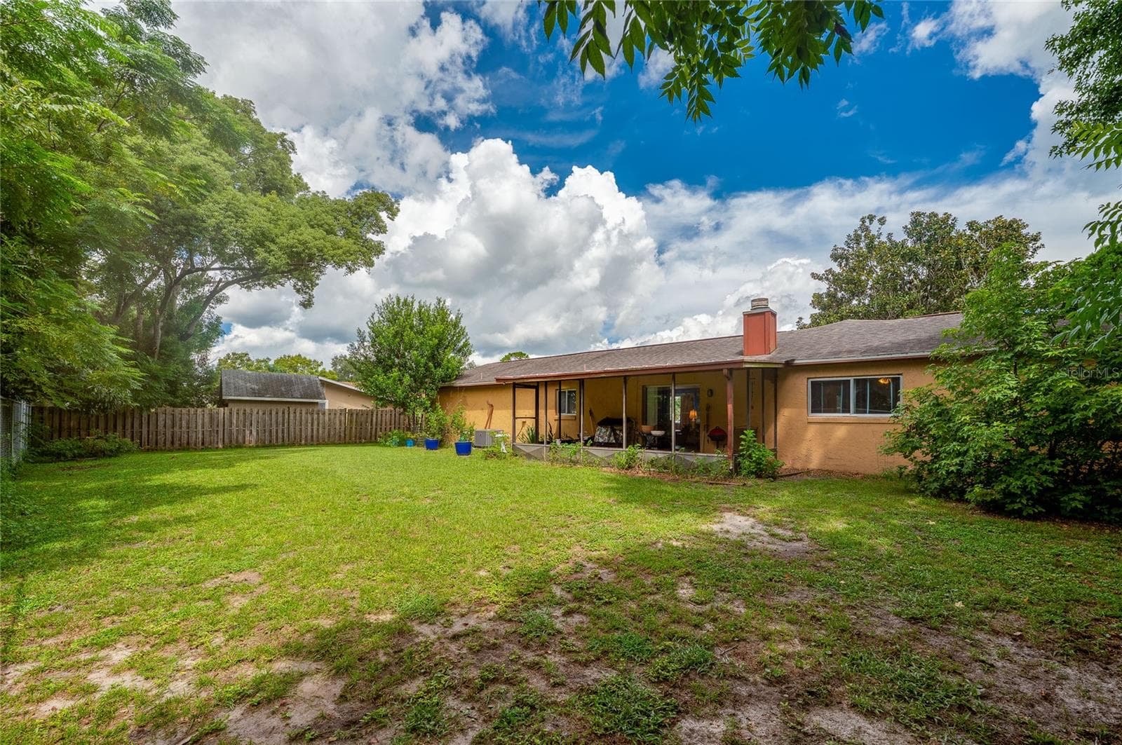 Large grassy backyard framed by mature shade trees and a fully enclosed fence along the rear of the property. - 146 WESTWOOD DR, DAYTONA BEACH