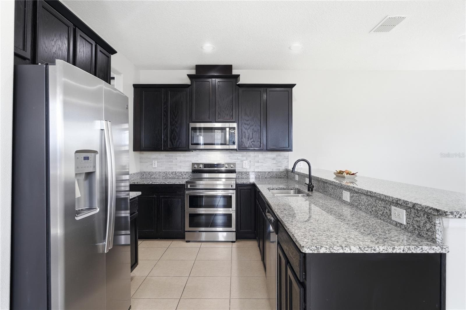 Open kitchen featuring granite countertops, stainless steel appliances and abundant cabinetry. - 2615 GIARDINO LOOP, KISSIMMEE