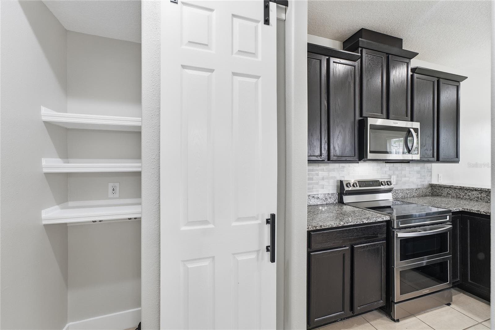 Convenient kitchen pantry with built-in shelving and a stylish barn door. - 2615 GIARDINO LOOP, KISSIMMEE