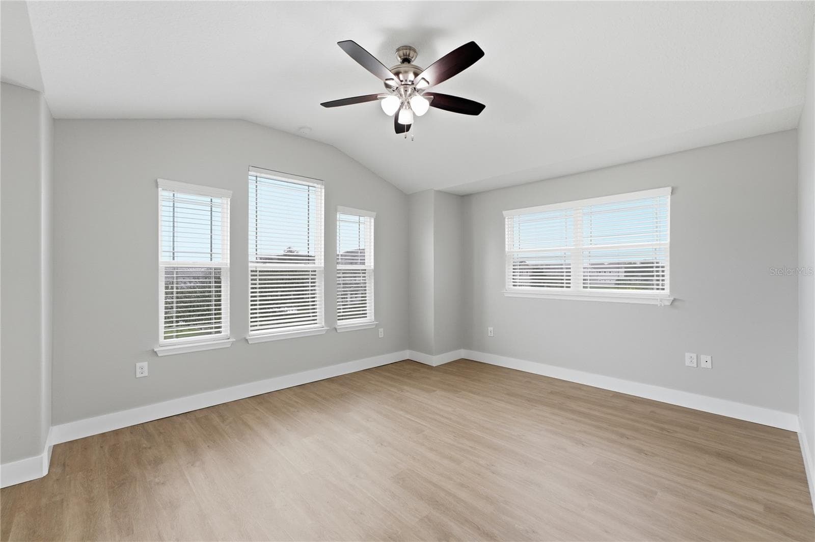 Expansive primary bedroom with vinyl plank flooring and abundant natural light from multiple windows. - 2615 GIARDINO LOOP, KISSIMMEE
