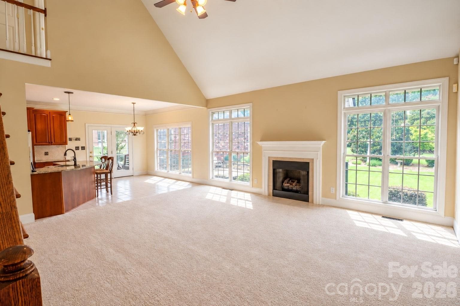 Large great room with gas fireplace, floor to ceiling windows, vaulted ceilings, and a ceiling fan - 1927 Windmere Drive, Monroe