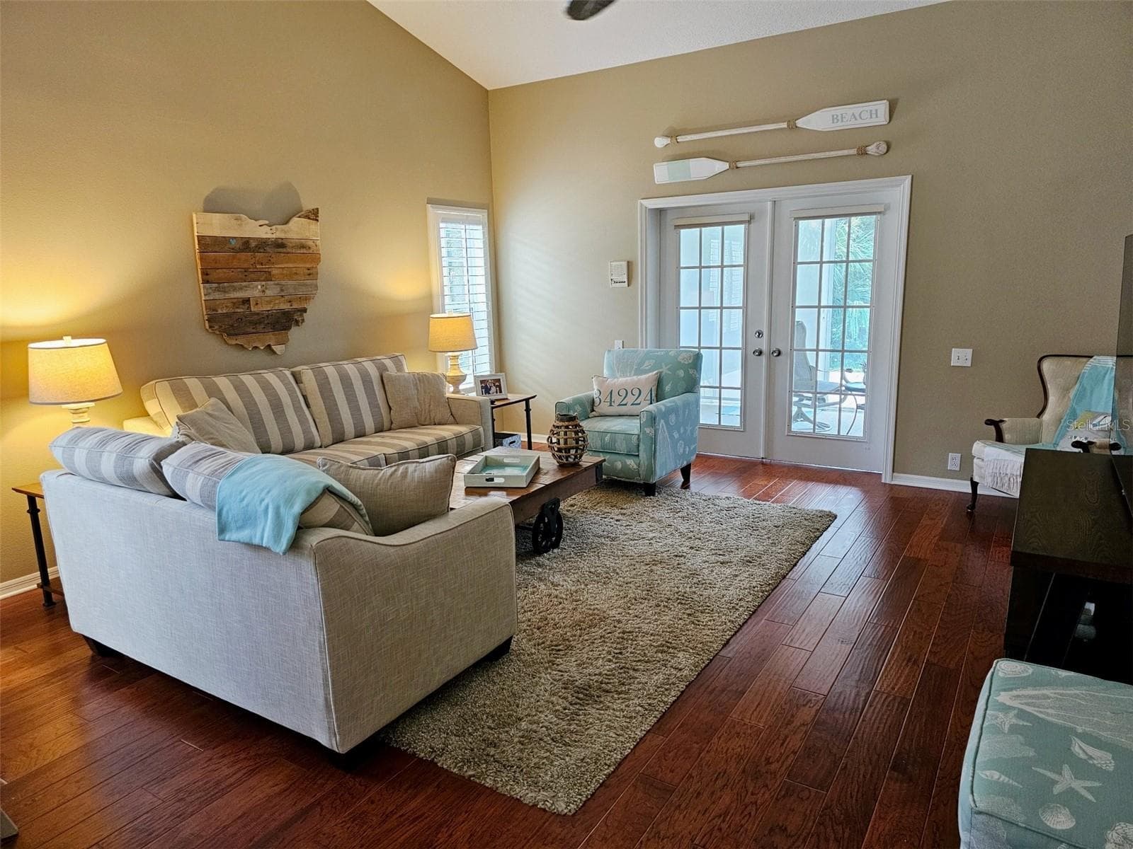 Living room features high ceilings, engendered wood floors, French doors to the glassed in lanai that opens to the patio. - 8351 CREEKVIEW LN, ENGLEWOOD