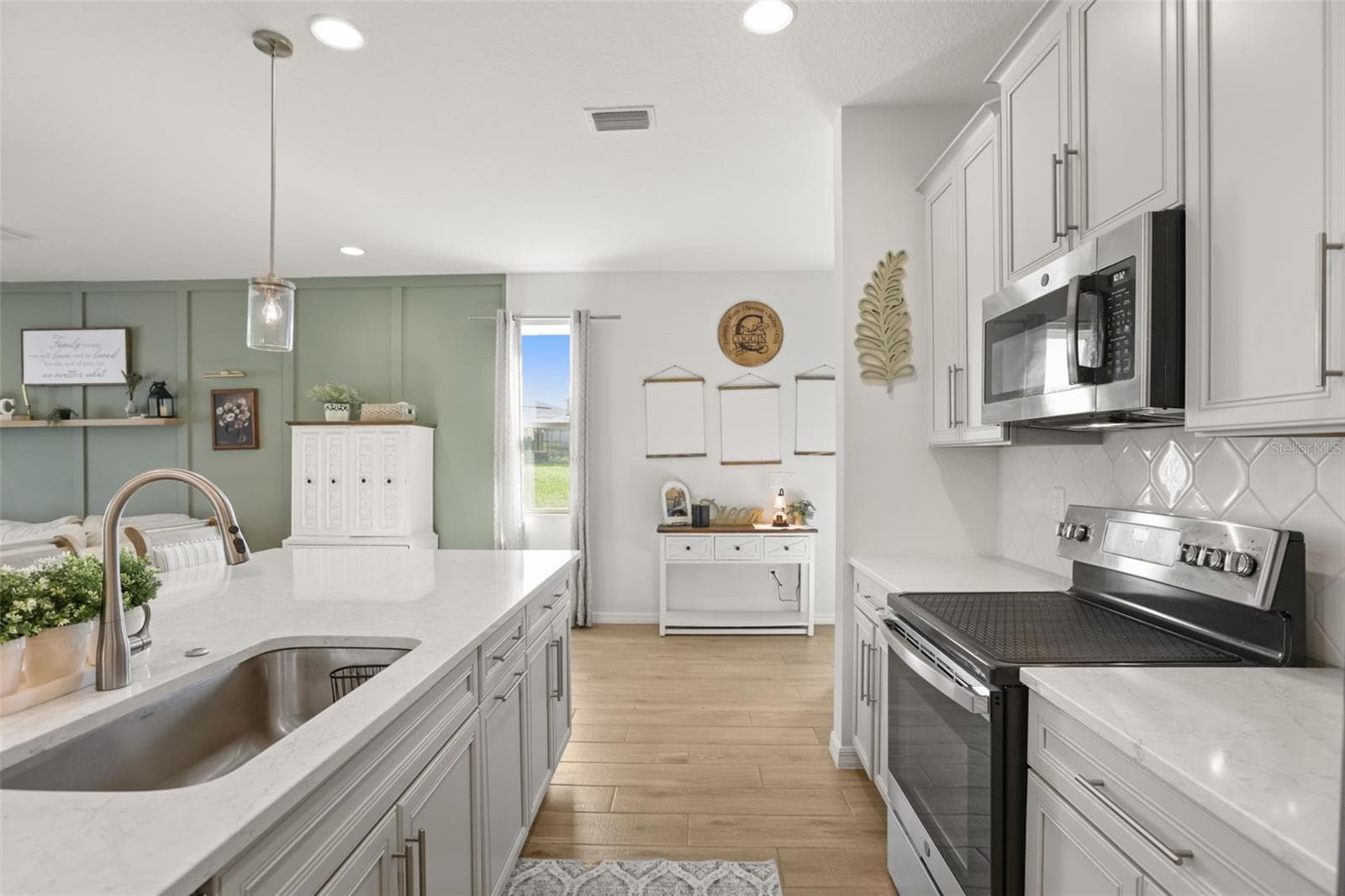 Well-designed kitchen with an oversized island, deep sink, quartz countertops, and plenty of cabinet storage. - 7104 DILLY LAKE AVE, GROVELAND