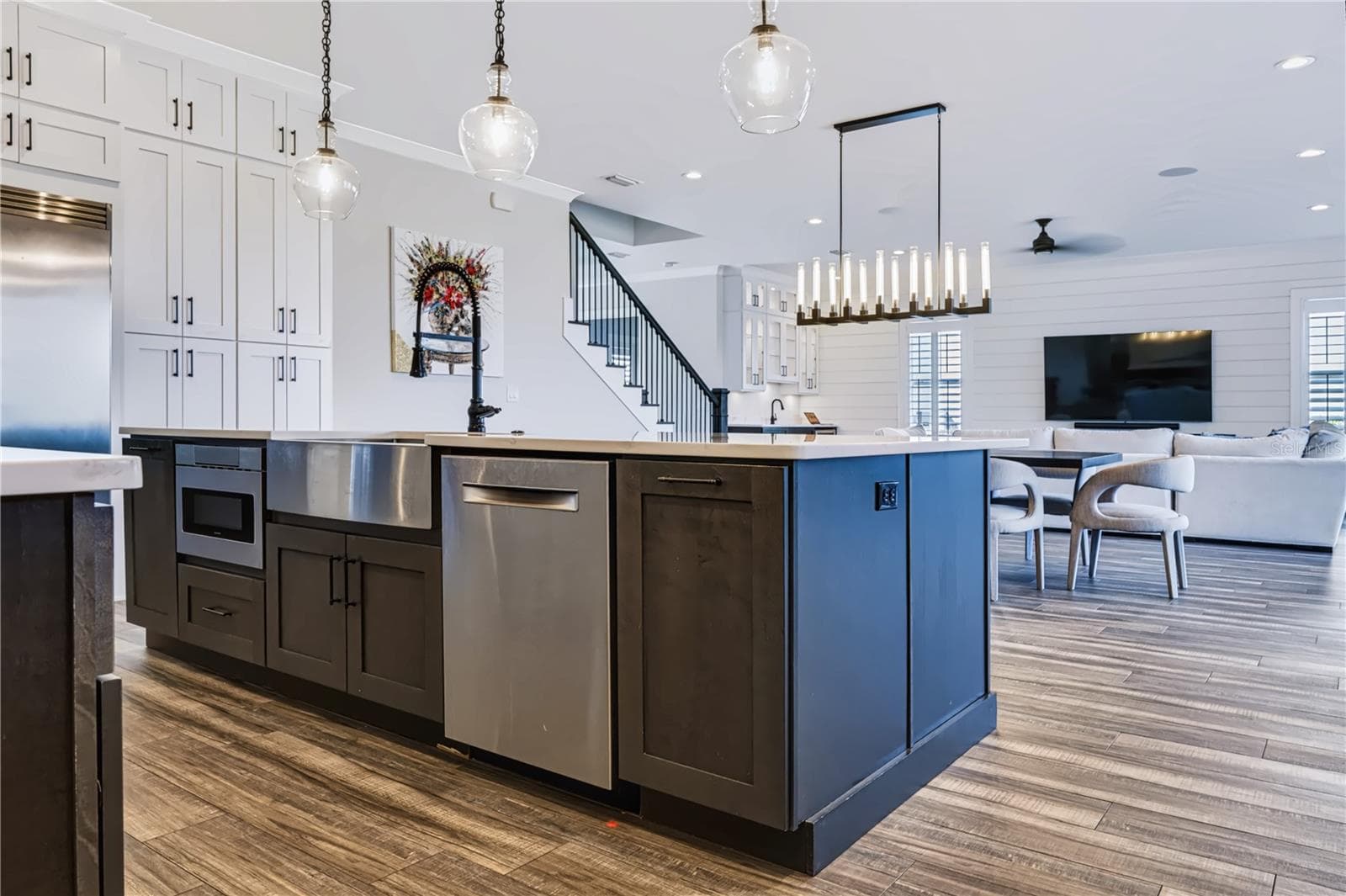 OVERSIZED CENTER ISLANDThe oversized center island incorporates an apron-front sink, dishwasher and under-counter microwave, with generous prep space and an open connection to the dining and living areas beyond. - 907 CELADON ST, WINTER GARDEN