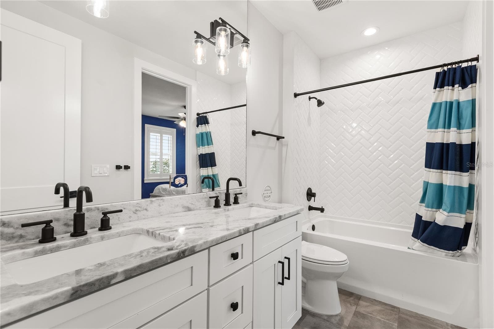 JACK & JILL FULL BATHShared between the two rear bedrooms, the Jack & Jill bath features dual sinks and a tub-and-shower combination with herringbone tile surround. - 907 CELADON ST, WINTER GARDEN