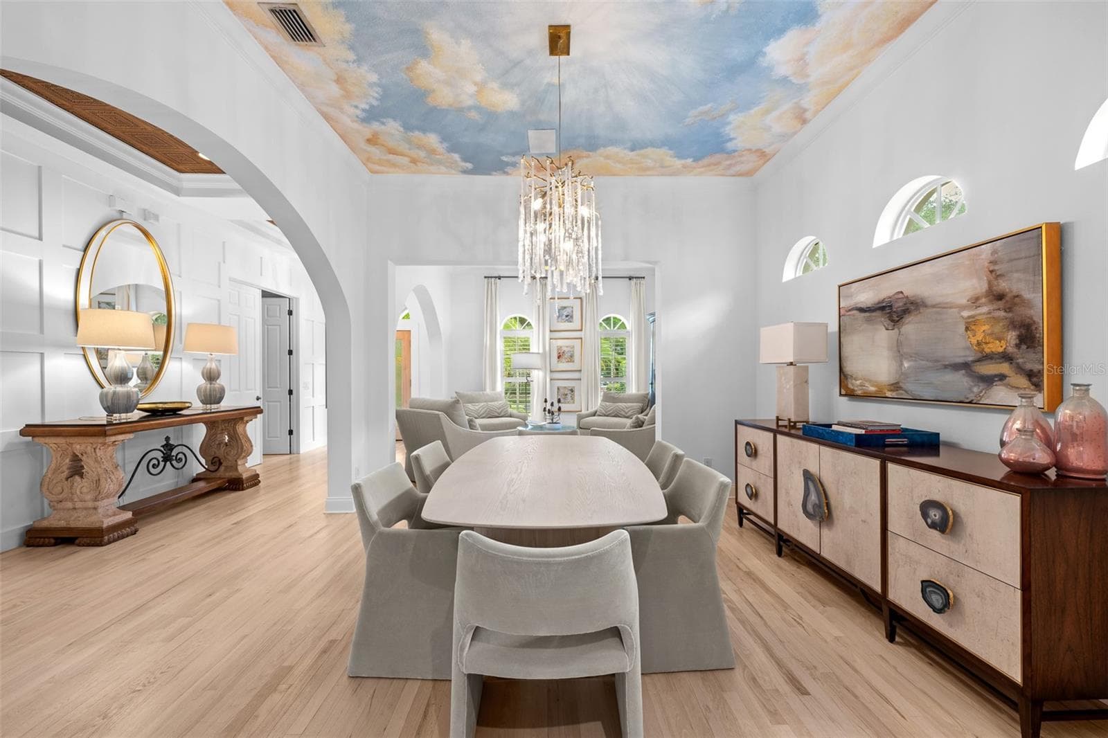 Formal dining space with a hand-painted sky ceiling mural, tiered chandelier, and built-in display shelving. - 1921 FLORESTA VIEW DR, TAMPA