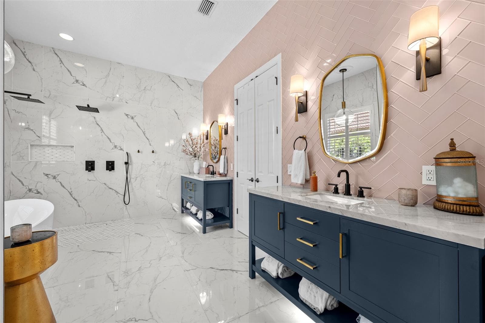 Primary Bathroom - Large-format marble-look tile, navy double vanity with brass hardware, and pink herringbone tile accent wall. - 1921 FLORESTA VIEW DR, TAMPA