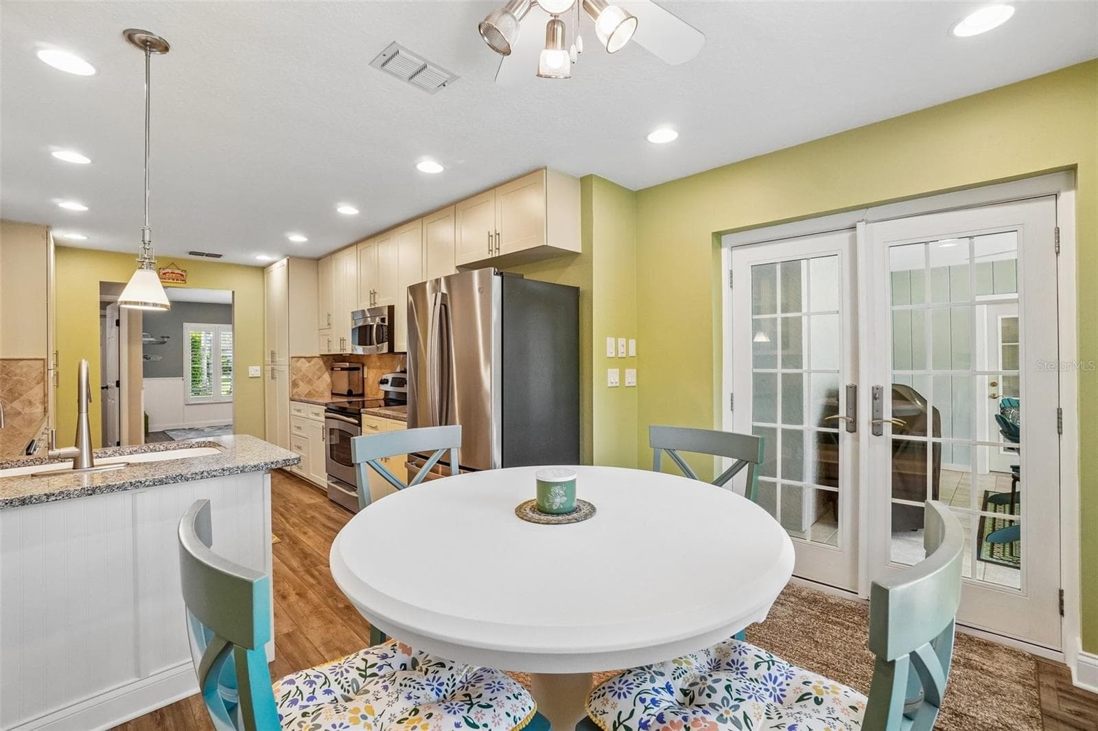 Breakfast Nook & Kitchen – This casual dining space connects seamlessly with the kitchen and features glass-paneled French doors that bring in additional natural light and provide access to the adjoining enclosed space. - 971 CORTLAND WAY, PALM HARBOR