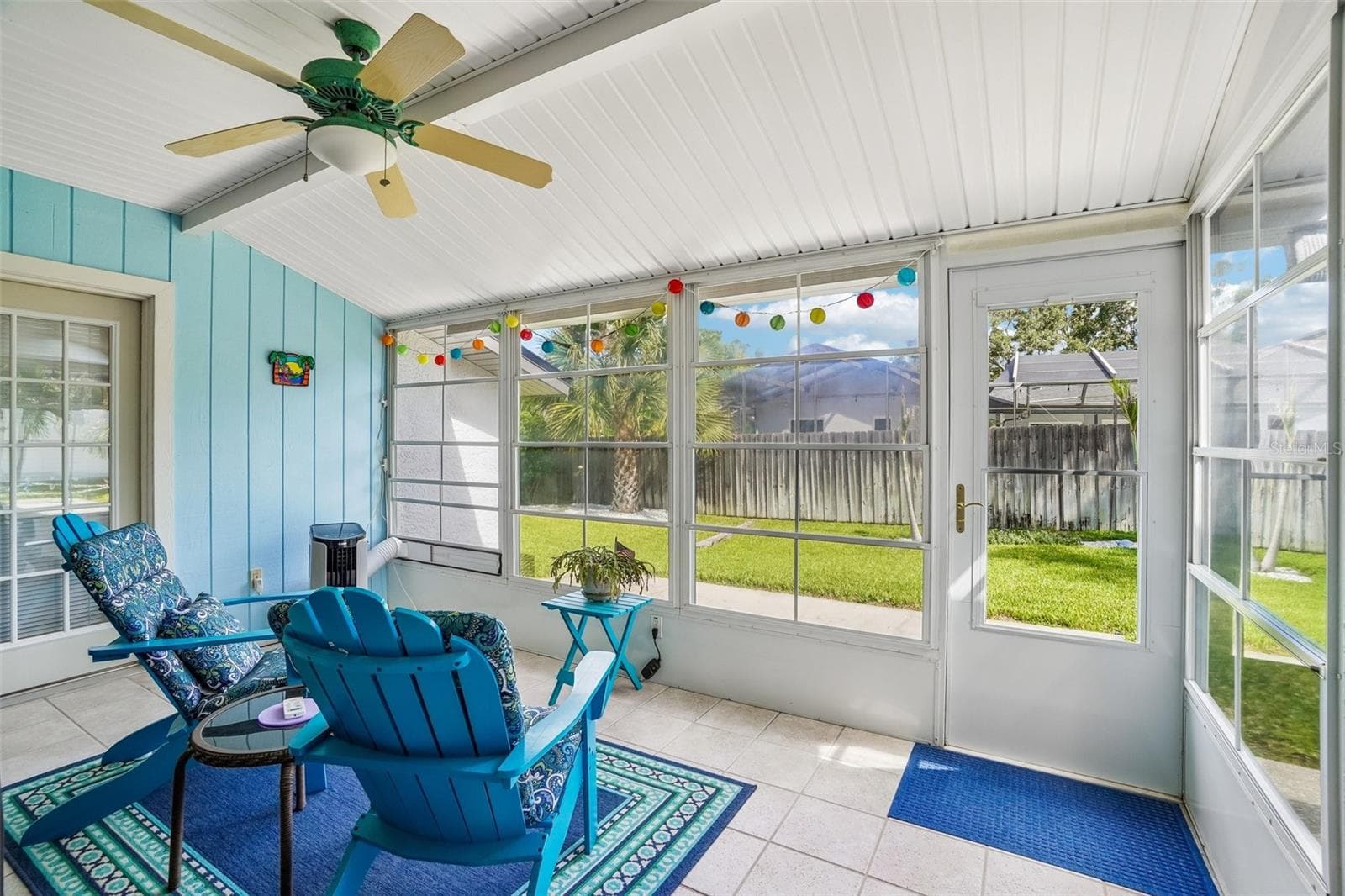 Enclosed Rear Patio – The bright enclosed rear patio offers tiled flooring, a ceiling fan, expansive screened/windowed walls, and direct access to the backyard for relaxed indoor-outdoor living. - 971 CORTLAND WAY, PALM HARBOR