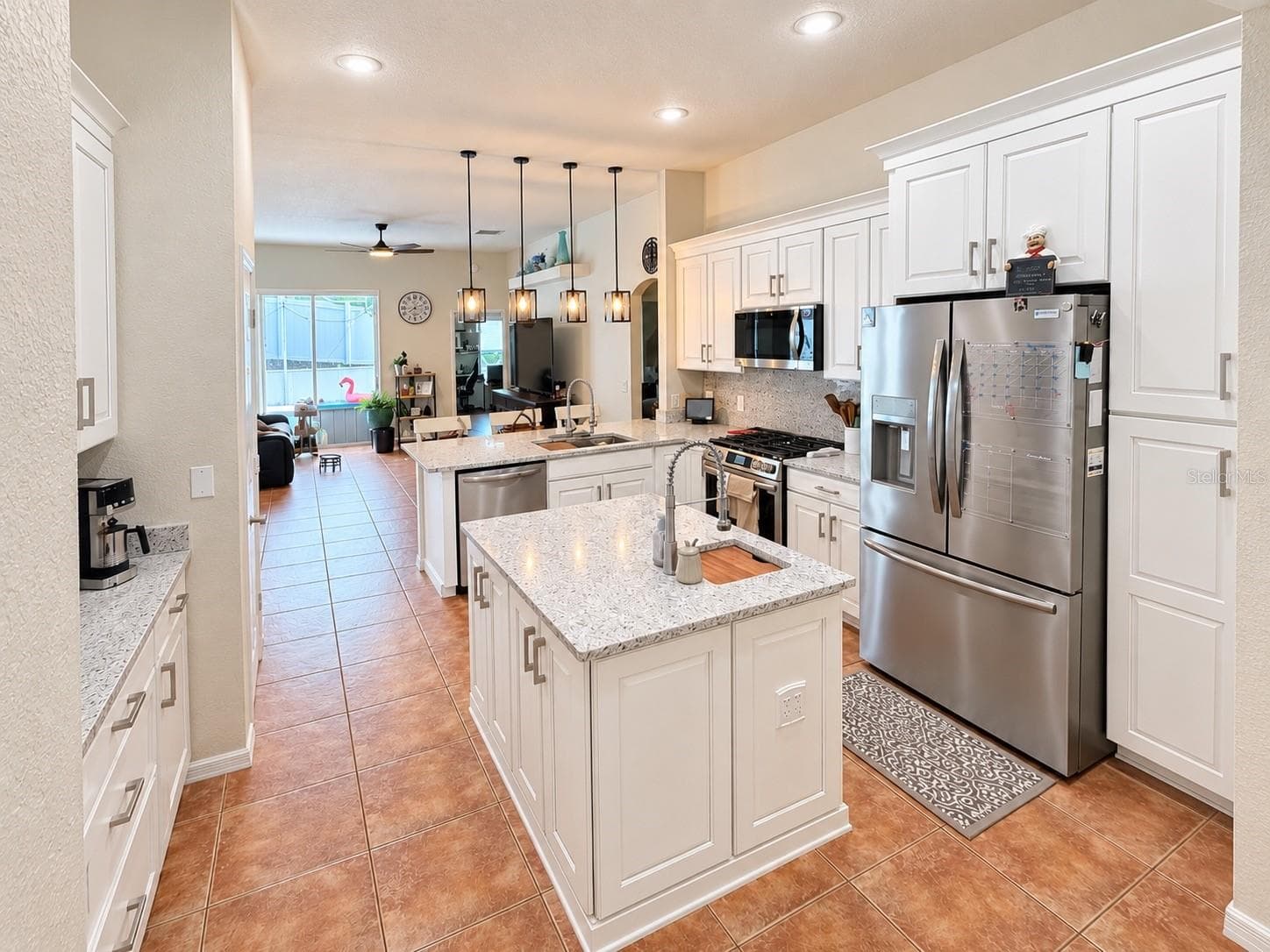 The updated kitchen features new cabinets and countertops, stainless steel appliances, soft-close cabinetry, pull-out storage for pots and pans, pull-out spice storage, Lazy Susan corner storage, additional counter seating, and a center island with prep sink. - 247 WESTWIND DR, DAVENPORT