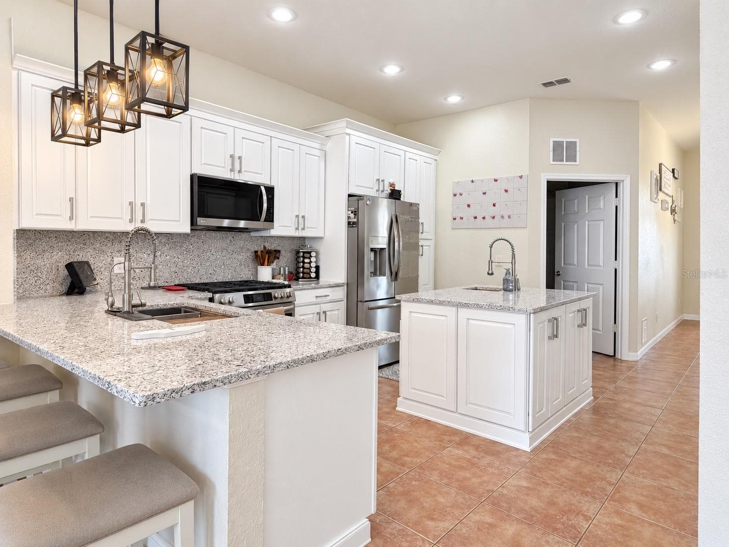 The updated kitchen features new cabinets and countertops, stainless steel appliances, soft-close cabinetry, pull-out storage for pots and pans, pull-out spice storage, Lazy Susan corner storage, additional counter seating, and a center island with prep sink. - 247 WESTWIND DR, DAVENPORT
