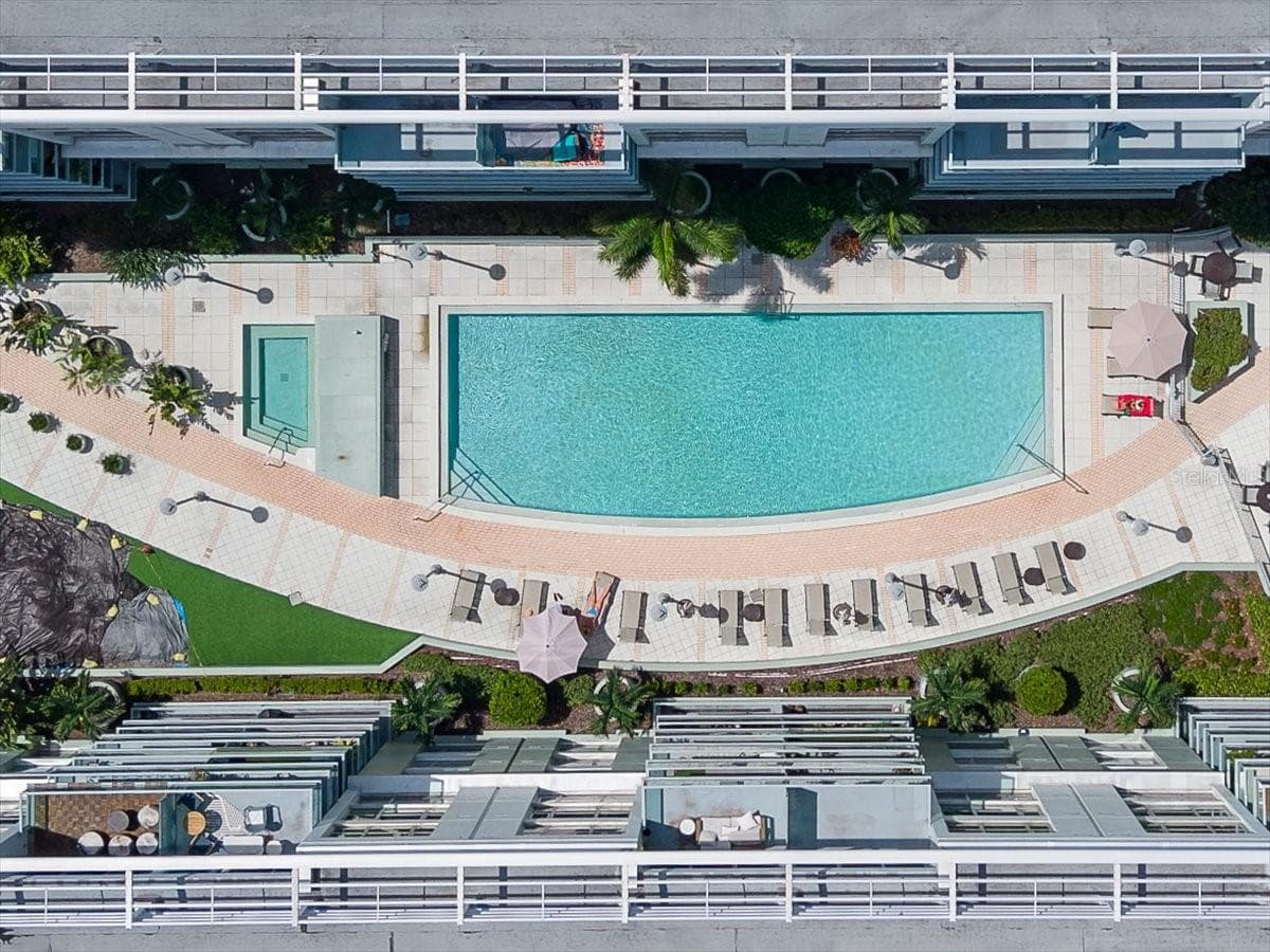 Bird’s-eye aerial view highlighting the resort-style pool deck, adjacent spa, expansive sun lounging area, and surrounding residential architecture. - 111 N 12TH ST #1704, TAMPA