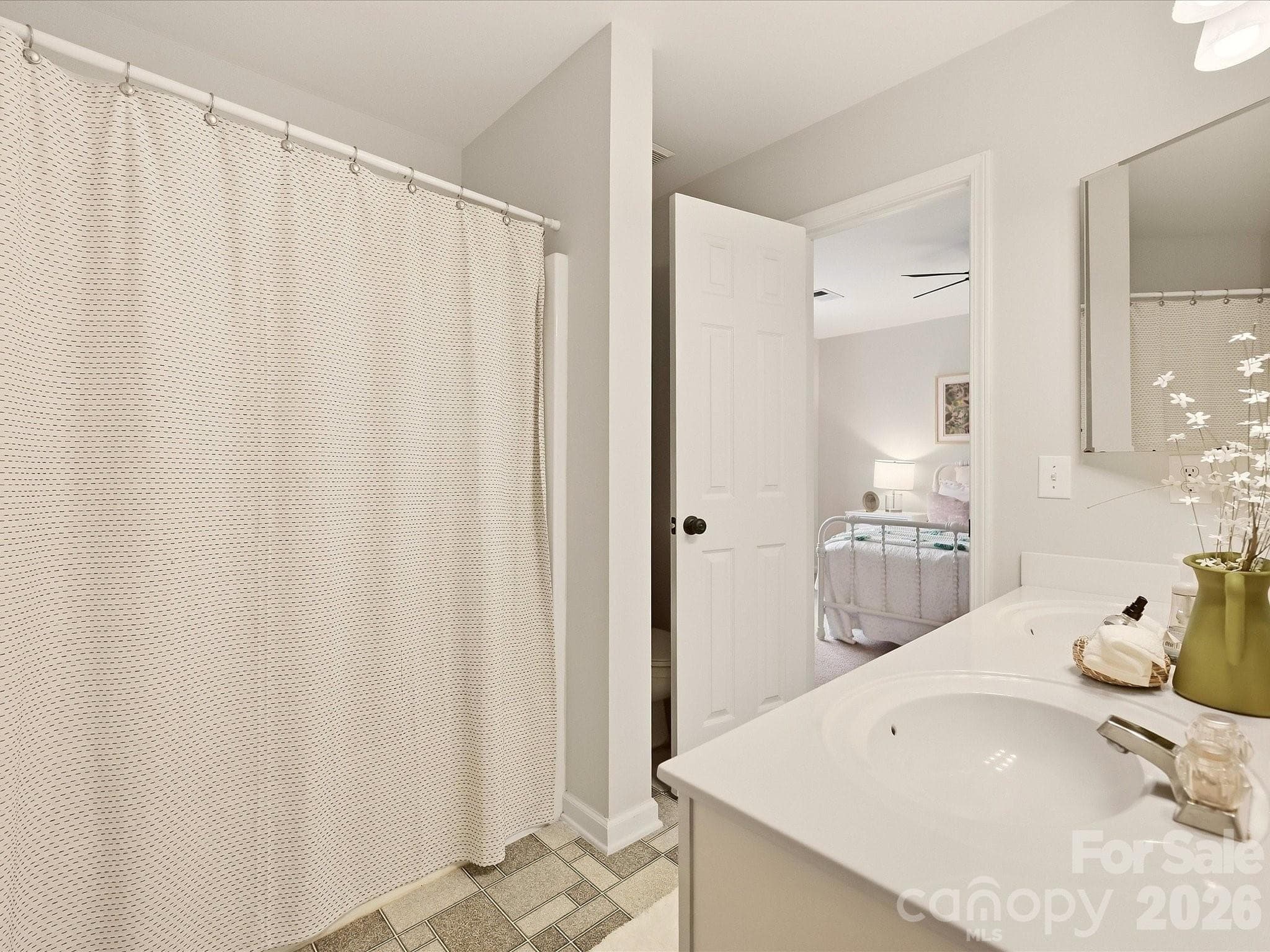 The Jack-and-Jill bath features a dual-sink vanity, tub/shower combination, and convenient access between two bedrooms for easy everyday functionality. - 16006 Lavenham Road, Huntersville