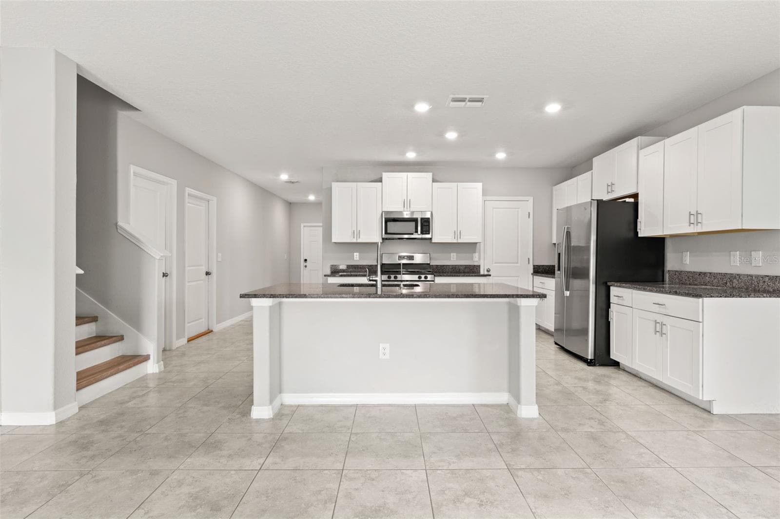 he kitchen’s oversized center island provides generous prep space and room for counter seating, framed by white shaker-style cabinetry, granite countertops, stainless appliances and recessed lighting. - 5061 WHITE CHICORY DR, APOLLO BEACH