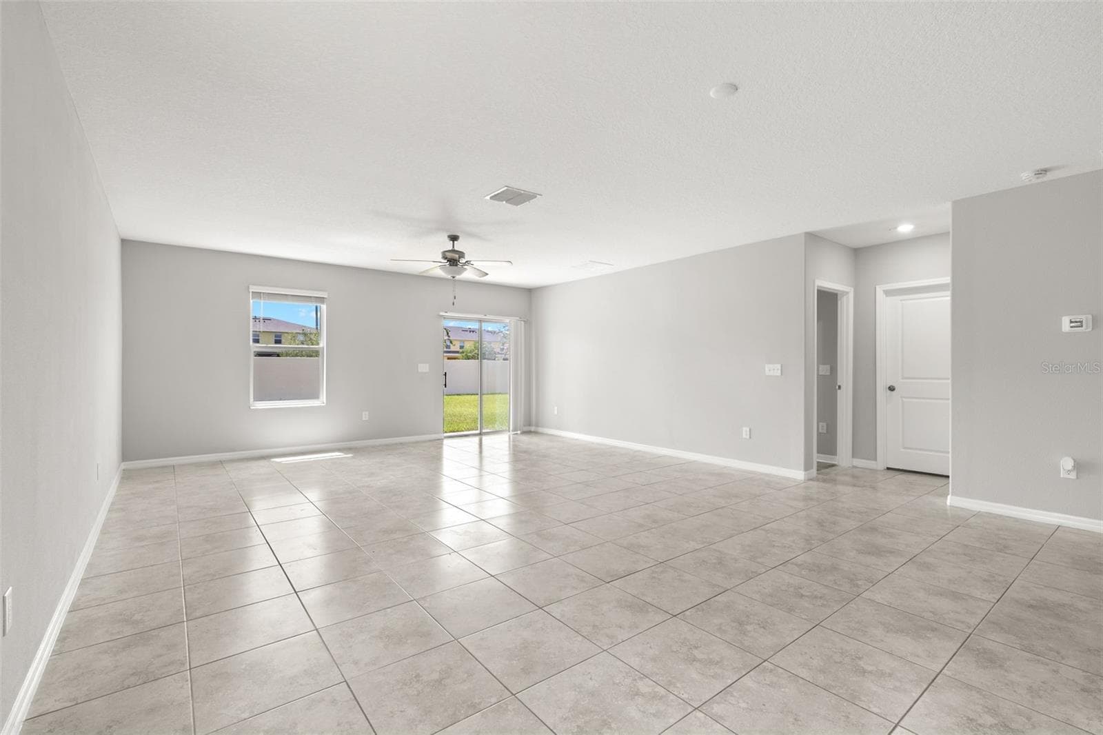 The great room offers plenty of space for both seating and dining, with fresh neutral paint, tile flooring and direct access to the backyard through sliding glass doors. - 5061 WHITE CHICORY DR, APOLLO BEACH