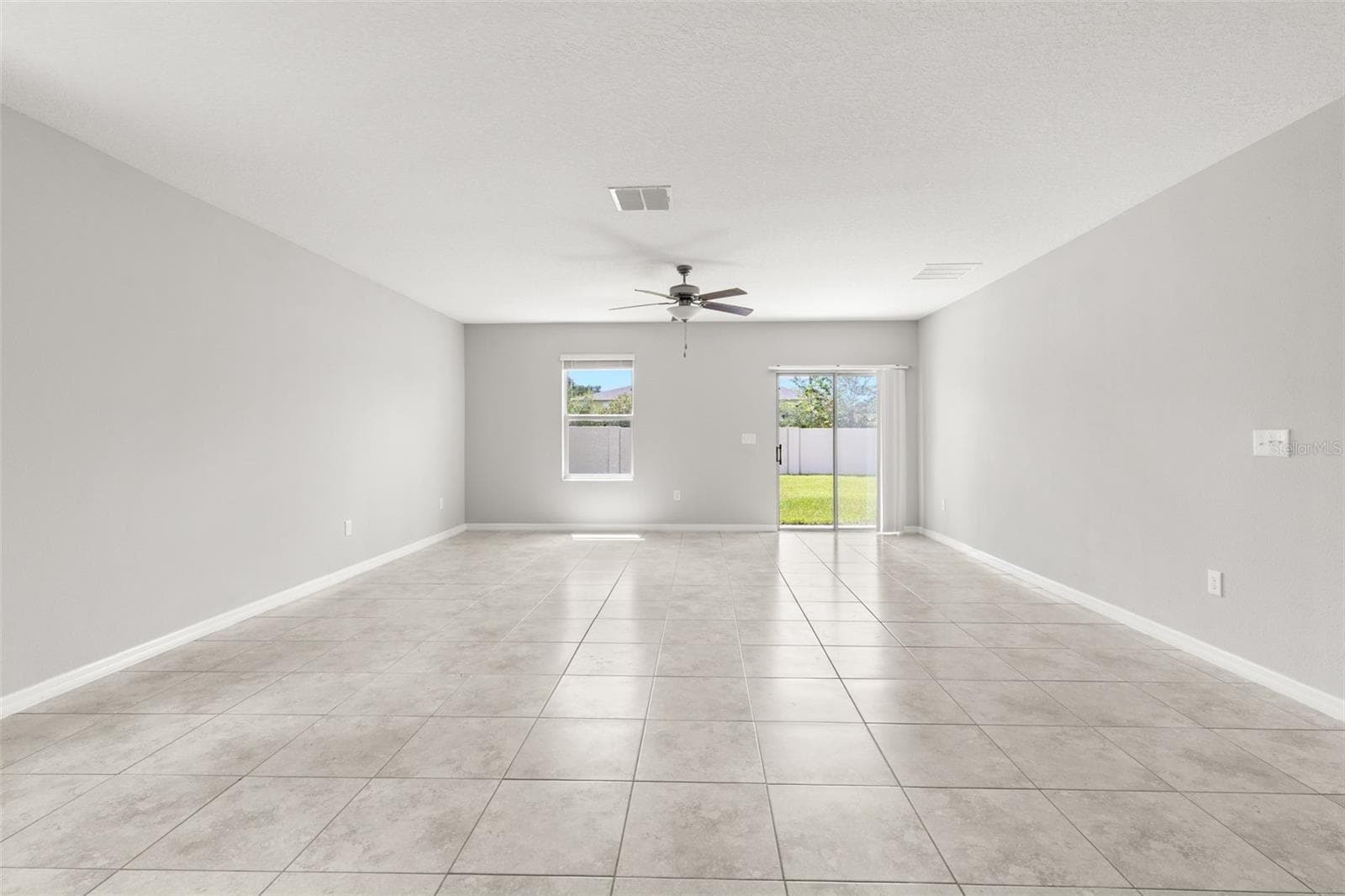 The great room offers plenty of space for both seating and dining, with fresh neutral paint, tile flooring and direct access to the backyard through sliding glass doors. - 5061 WHITE CHICORY DR, APOLLO BEACH